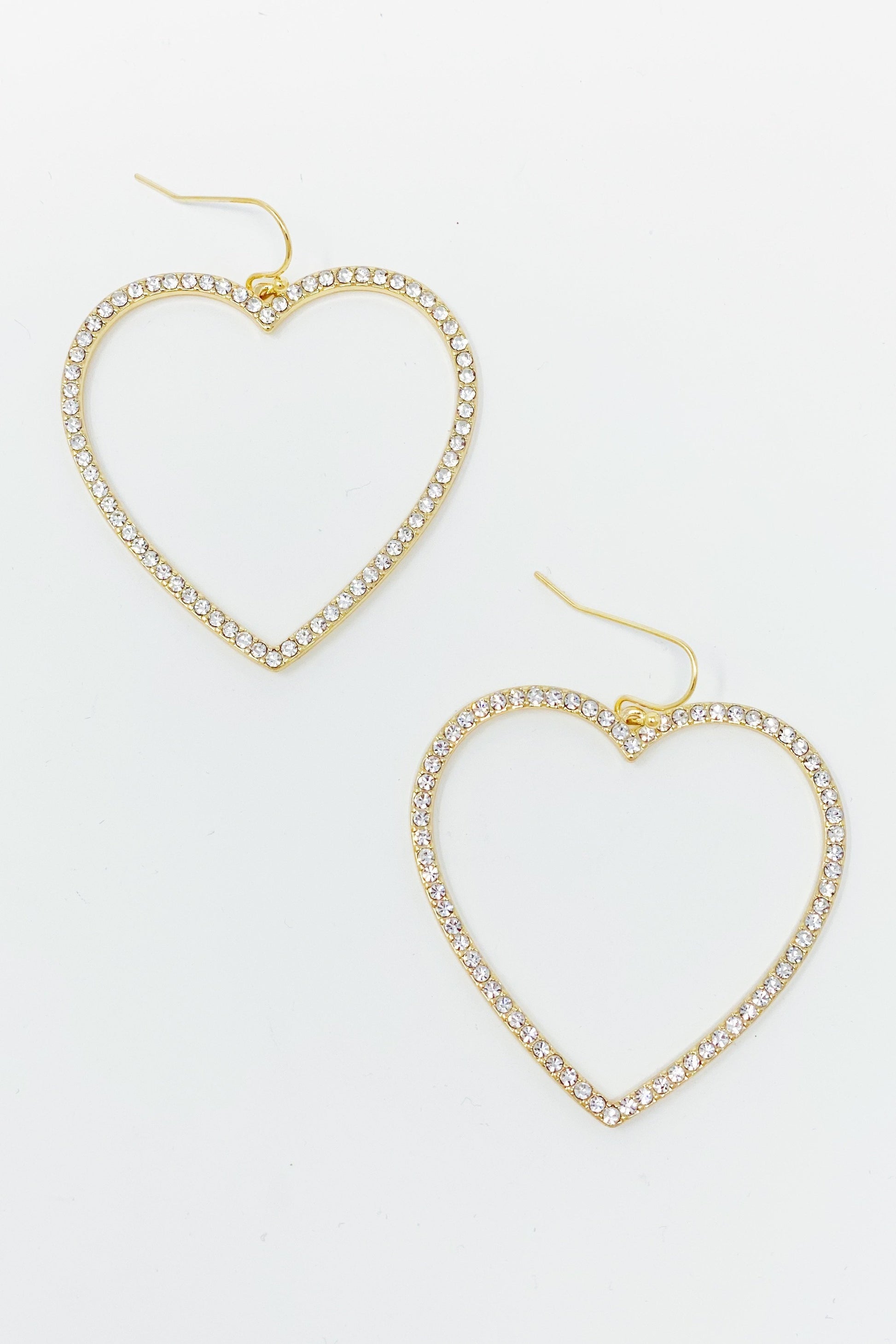 The My Precious Heart Earrings by Ellison + Young feature two gold heart-shaped designs adorned with rhinestones, shown on a white background.
