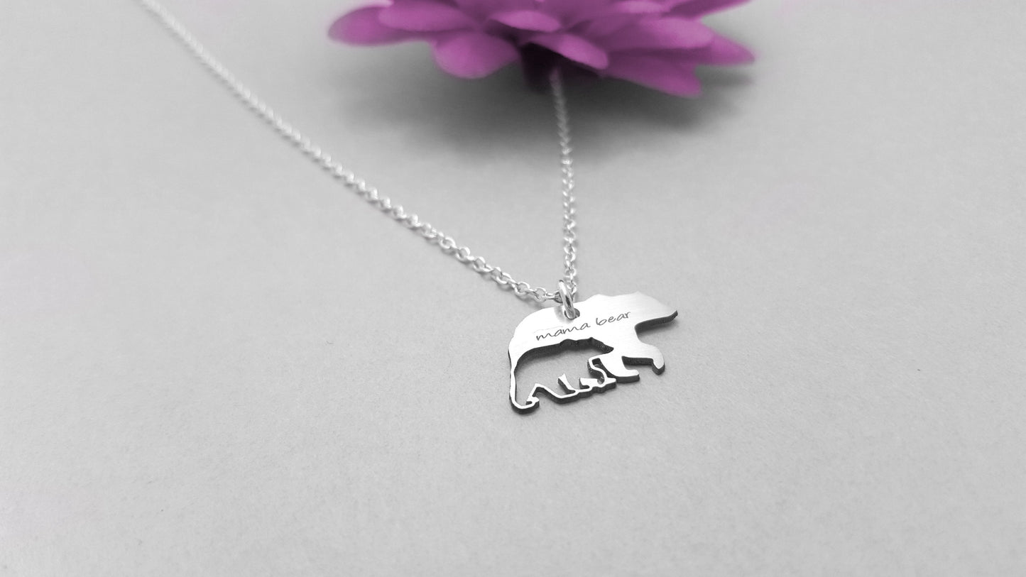 The Mama Bear and Cub Necklace by Sincerely Silver is a silver piece with a bear-shaped pendant featuring three cubs and inscribed with mama bear.
