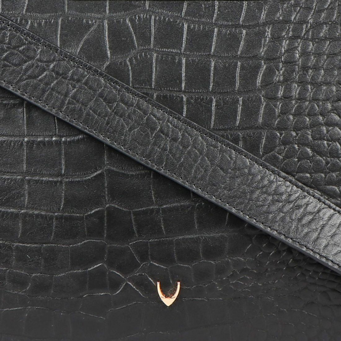 A Hidesign leather handbag in black features a textured design, rectangular cutout handle, and detachable shoulder strap.
