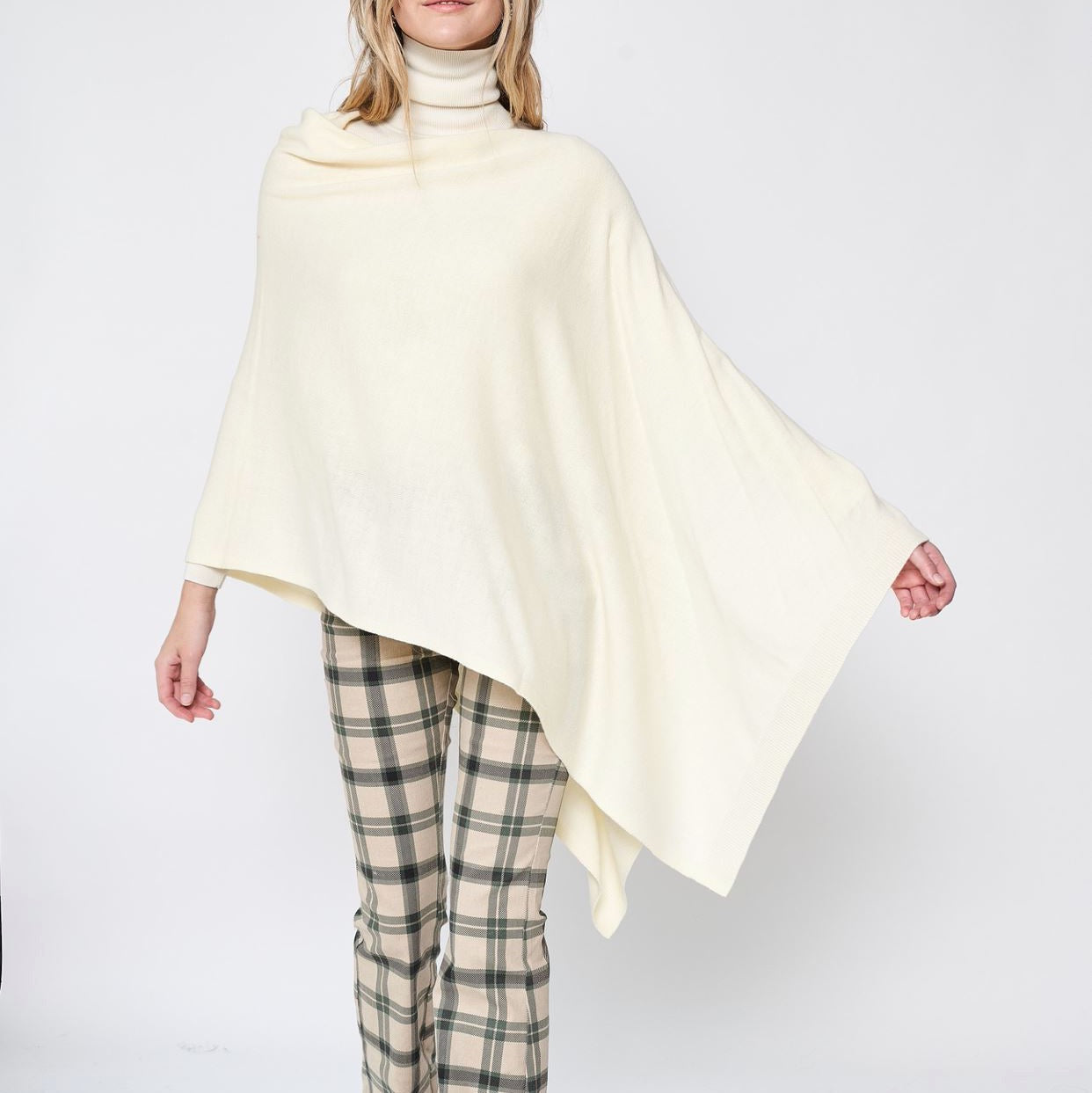 Someone wearing the Take With Me Travel Poncho by Ellison + Young with plaid pants against a plain white background.