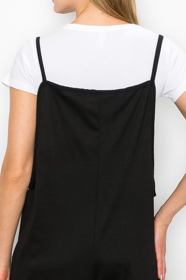 A person models the Stylespect Cropped Bottom Wide Leg Oversized Jumpsuit in black, paired with a white t-shirt and white sneakers, set against a plain white backdrop.