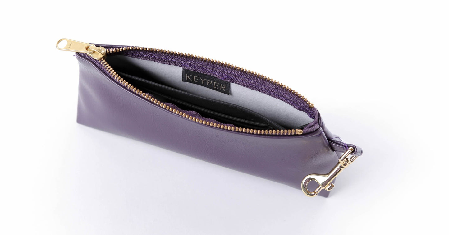 A Pretty Purple Vegan Leather Bag by KEYPER features a gold zipper and strap, showcased on a white background.