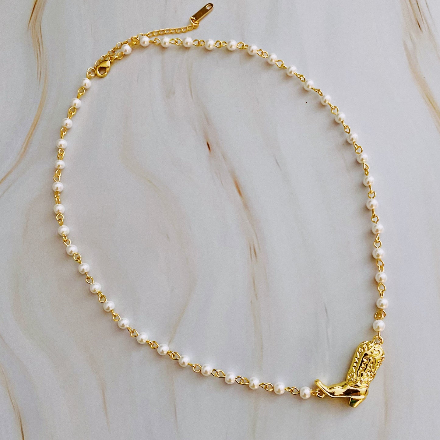 Ellison + Youngs Cowgirl Boot Pearl Chain Necklace is displayed on a marble surface.