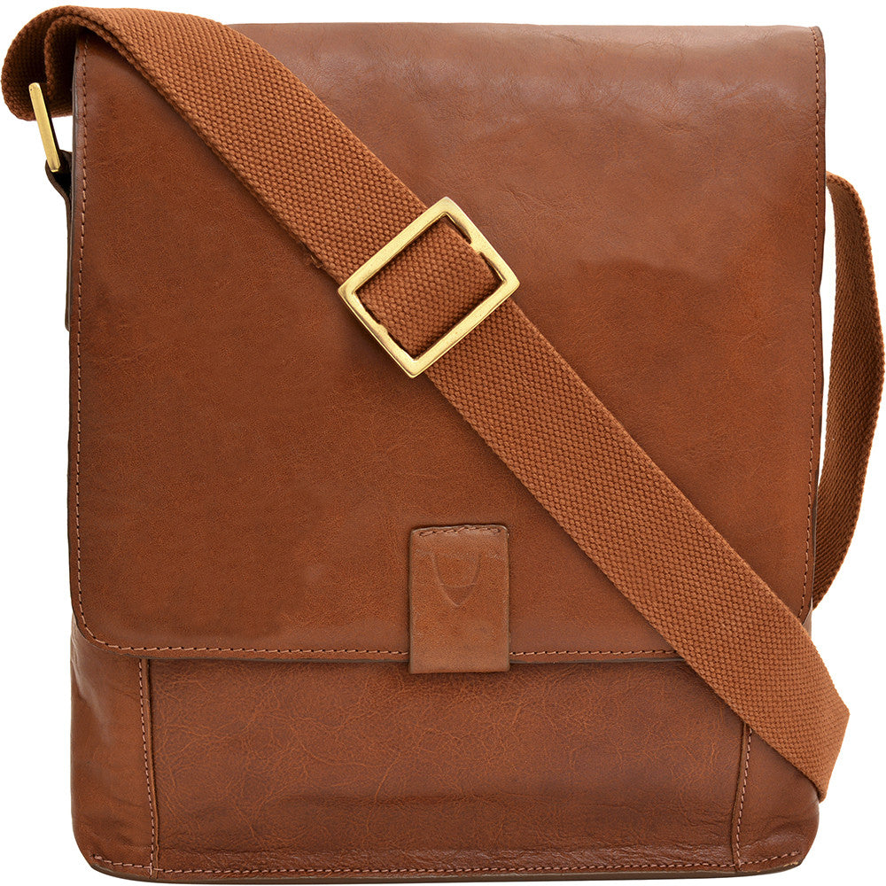 The Aiden Genuine Leather Mini Crossbody by Hidesign is a brown leather shoulder bag featuring a flap cover and an adjustable fabric strap with a brass buckle.