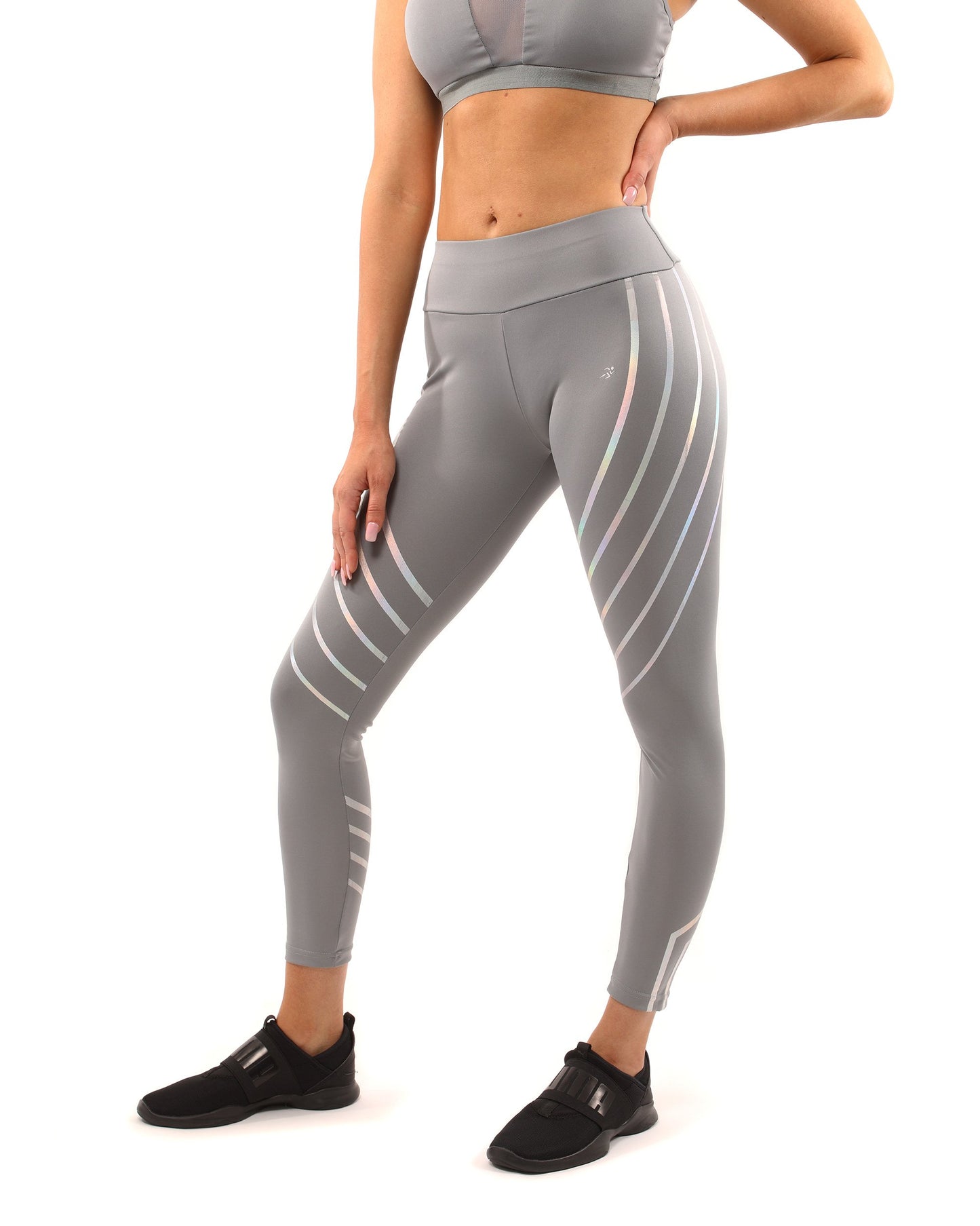 A woman in Savoy Actives grey Laguna Leggings stands on outdoor steps, adjusting her top while facing away from the camera.