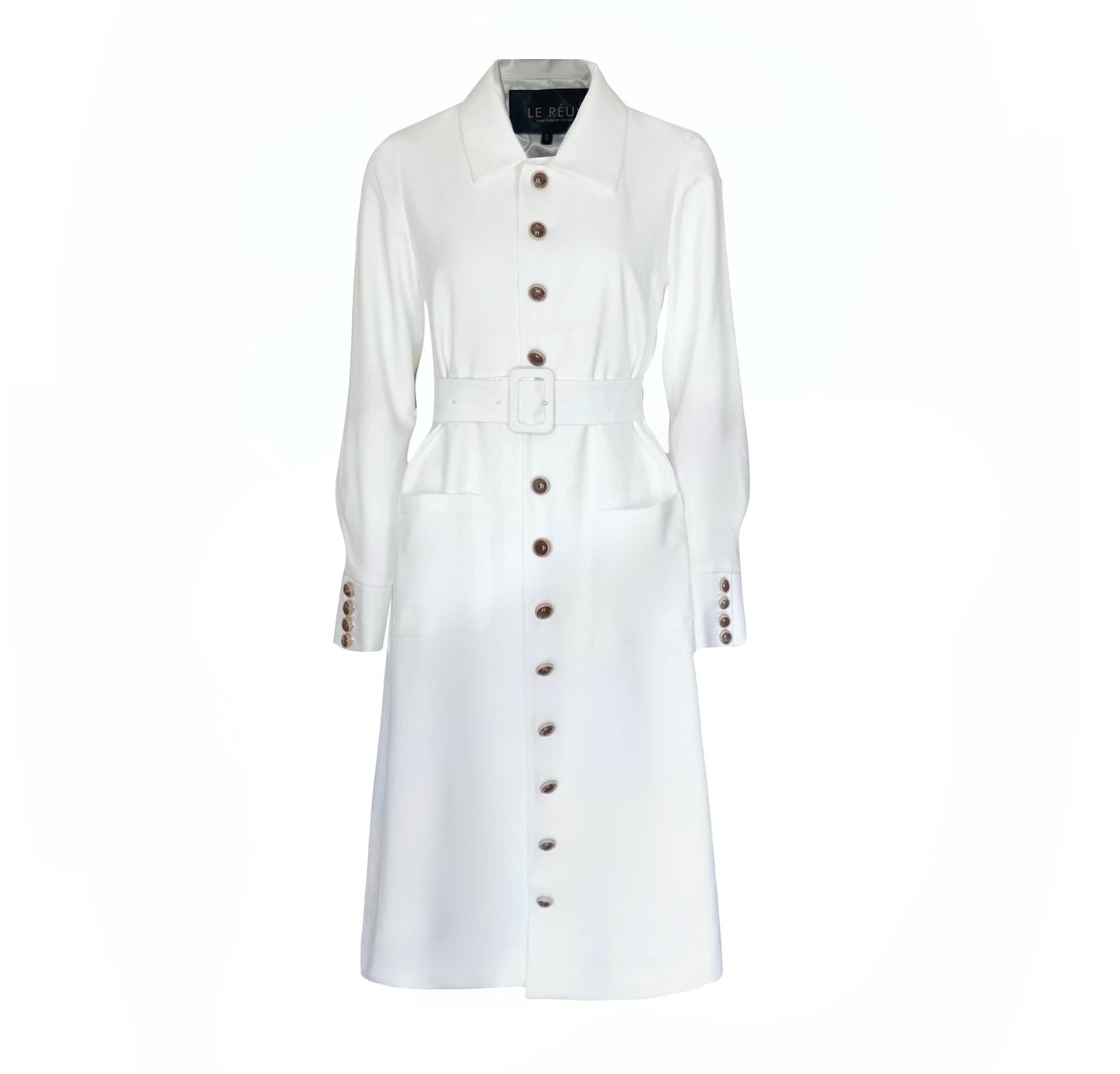 The Monique White Coat by Le Réussi® is a long-sleeve trench coat featuring a collar, button closure, matching belt, and cuff buttons.