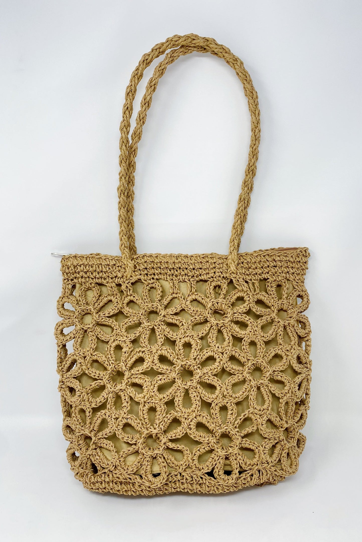 A person smiles while standing outdoors with a clear blue sky and trees in the background, wearing a yellow striped sweater and holding an Ellison + Young Hand Made Muted Floral Tote.