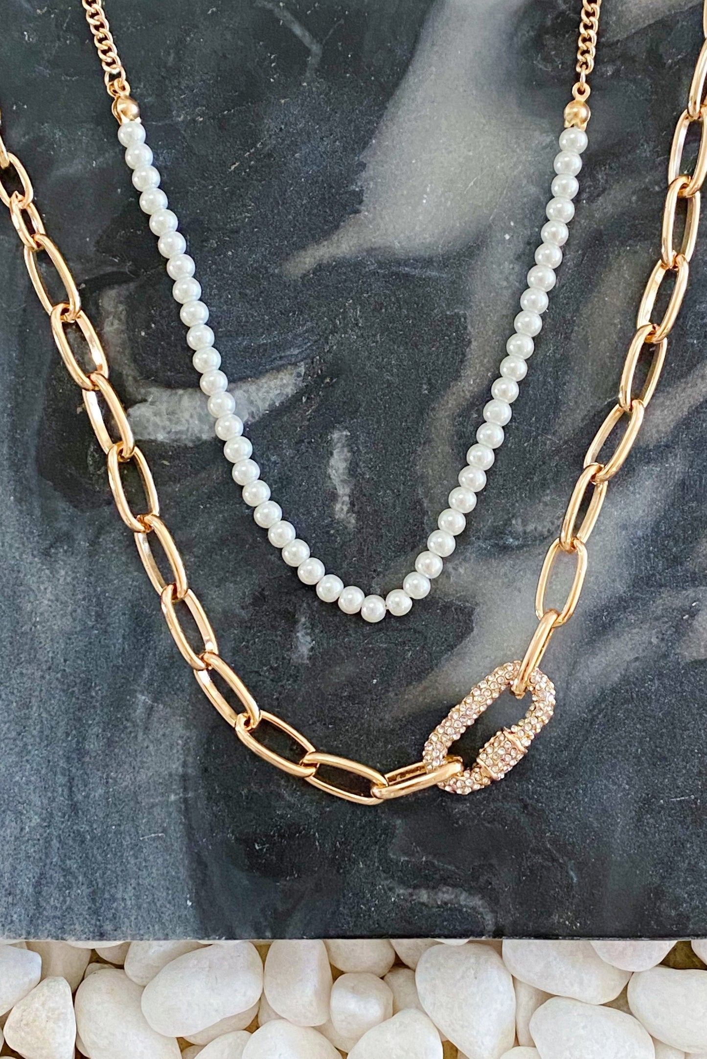 A person wearing the Ellison + Young Classic Duo Layered Pearl Necklace Set with gold links and pearl accents, plus a simple strand of pearls.