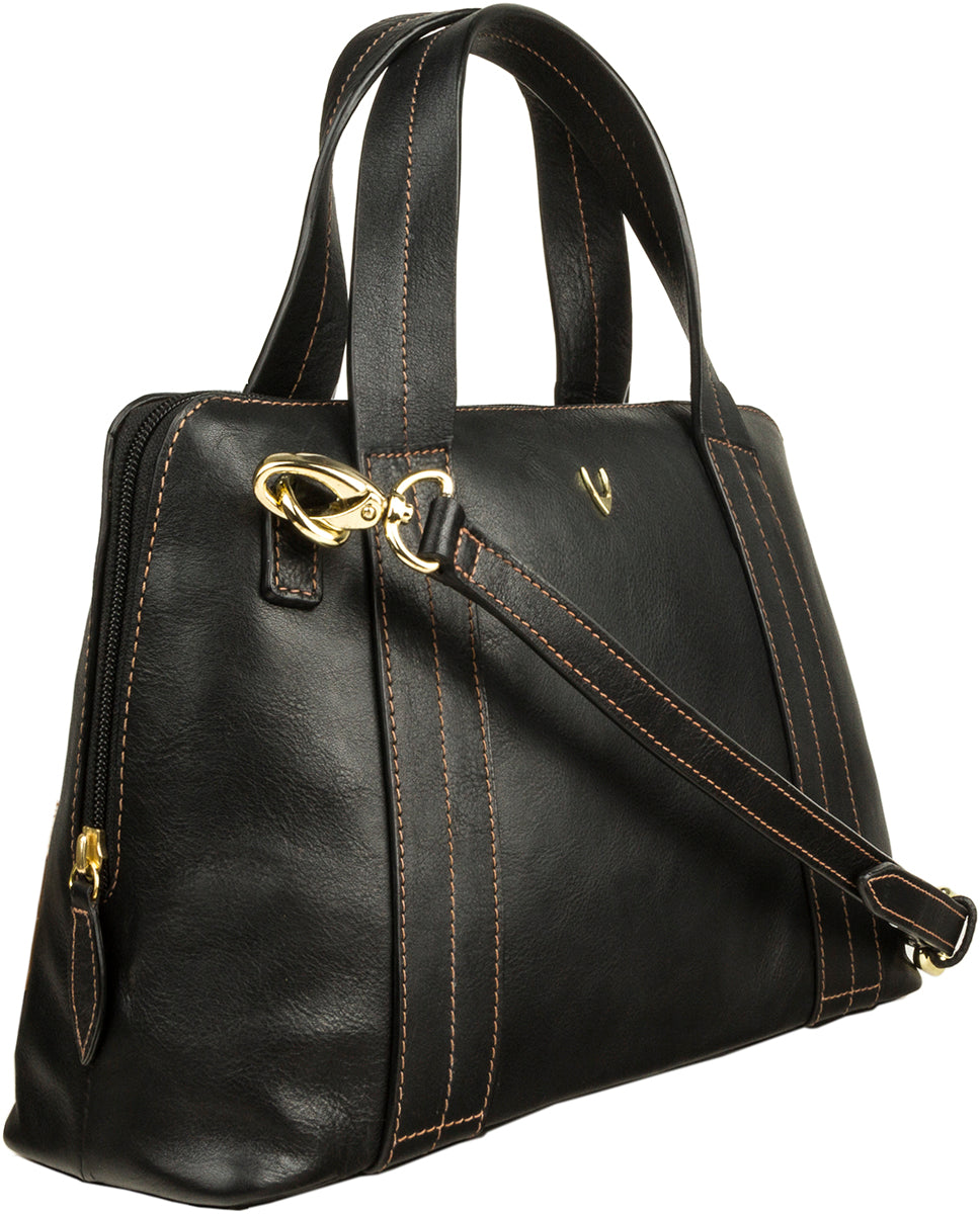 The Hidesign Cerys Leather Satchel is a black handbag with brown stitching, gold hardware, two handles, and an adjustable shoulder strap.