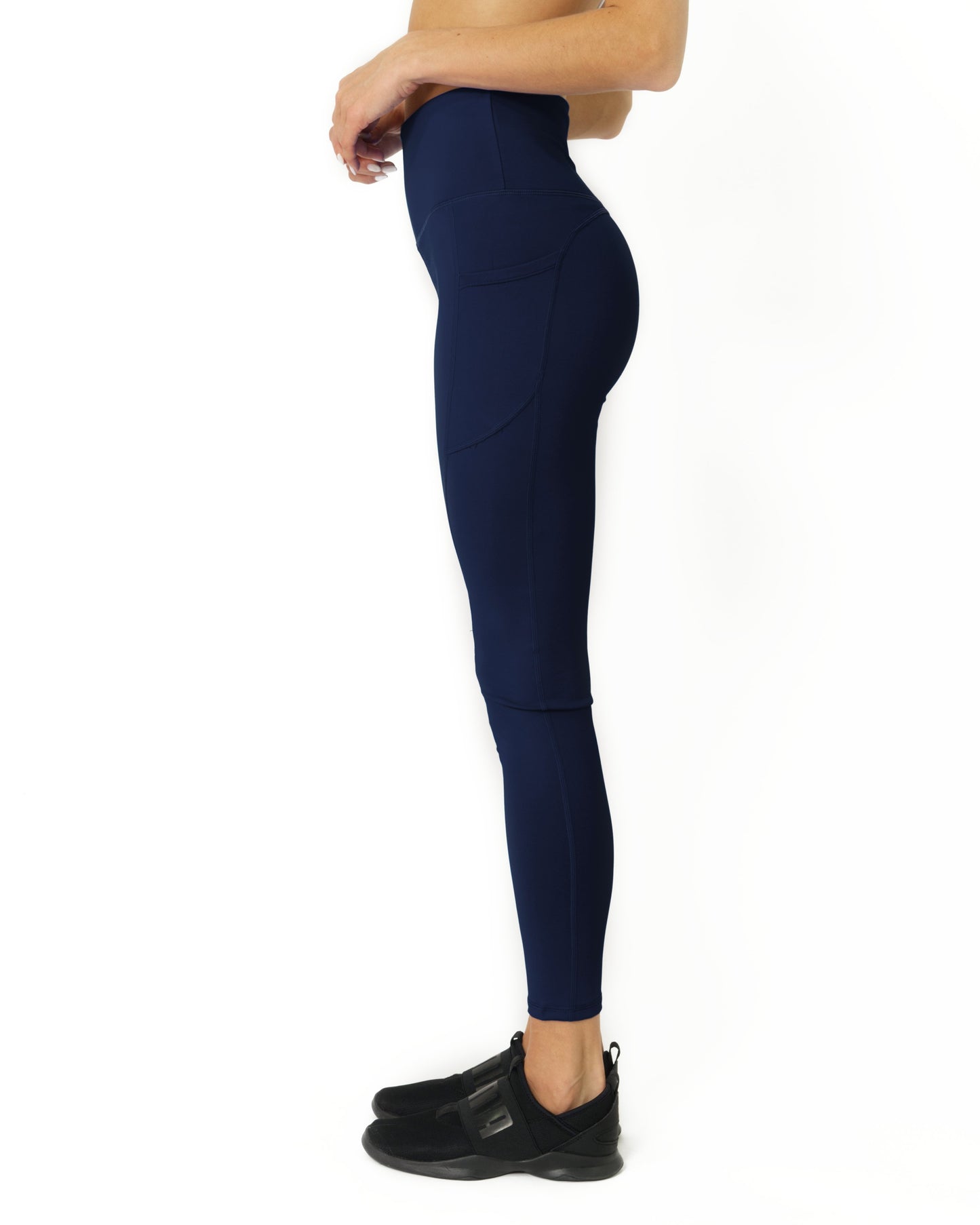 A person wearing Savoy Actives High Waisted Yoga Leggings in Navy Blue and black shoes stands against a white background.