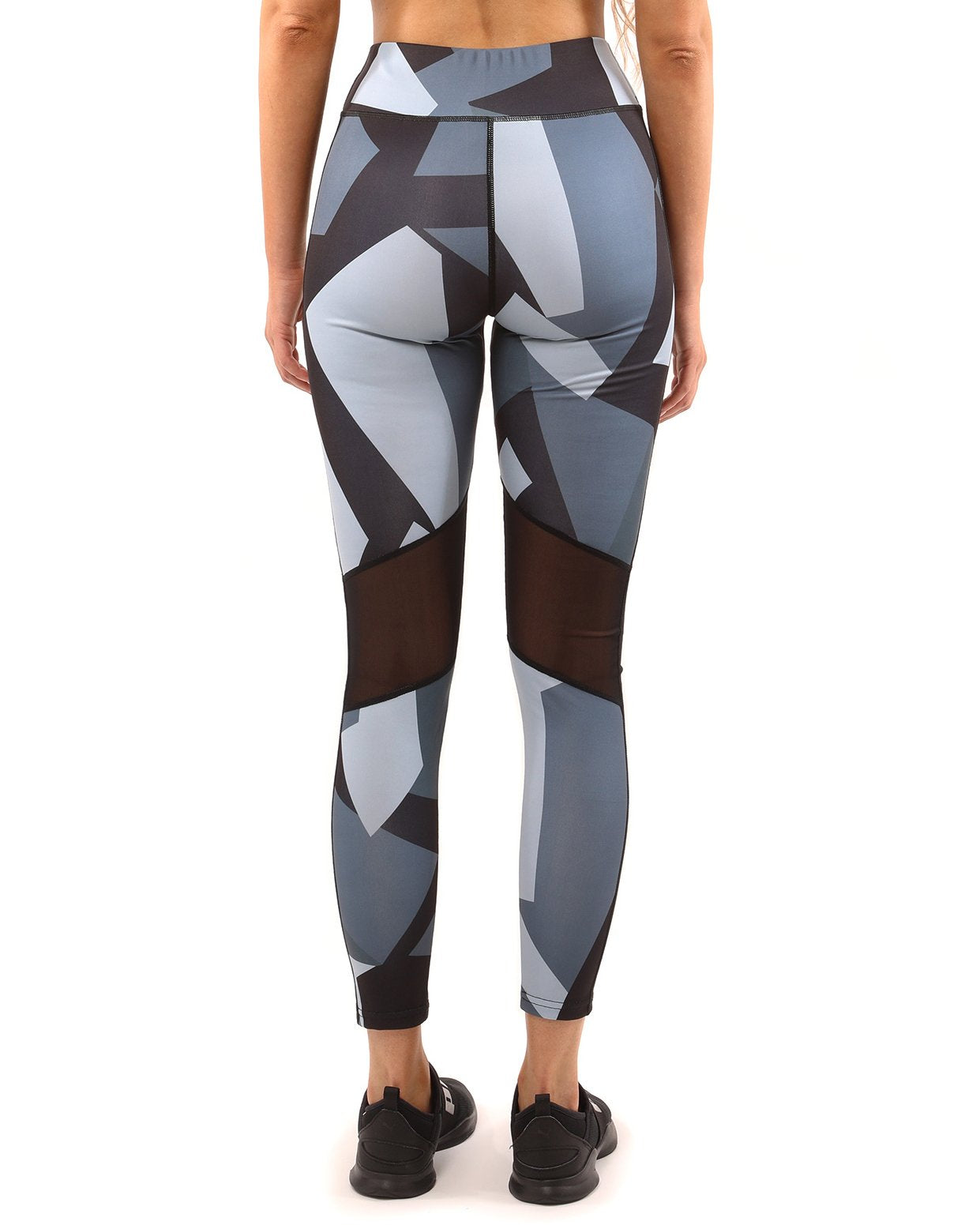 A person wearing the Savoy Active Bondi Set, consisting of geometric-patterned black and grey leggings and a sports bra, stands against a white background.