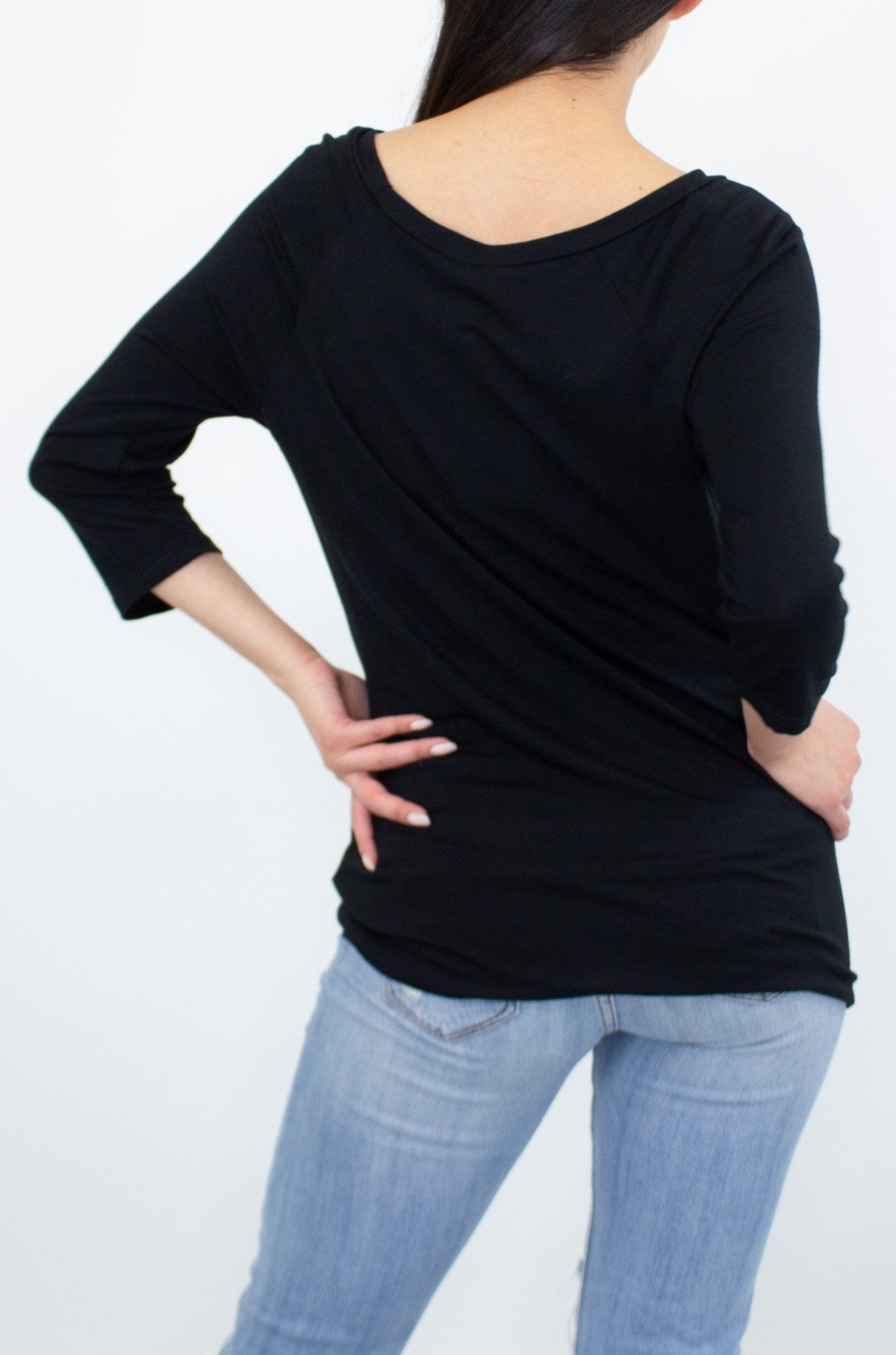 A person wearing the Stylespect Twisted Front Comfortable Top in black and ripped jeans stands against a plain background.