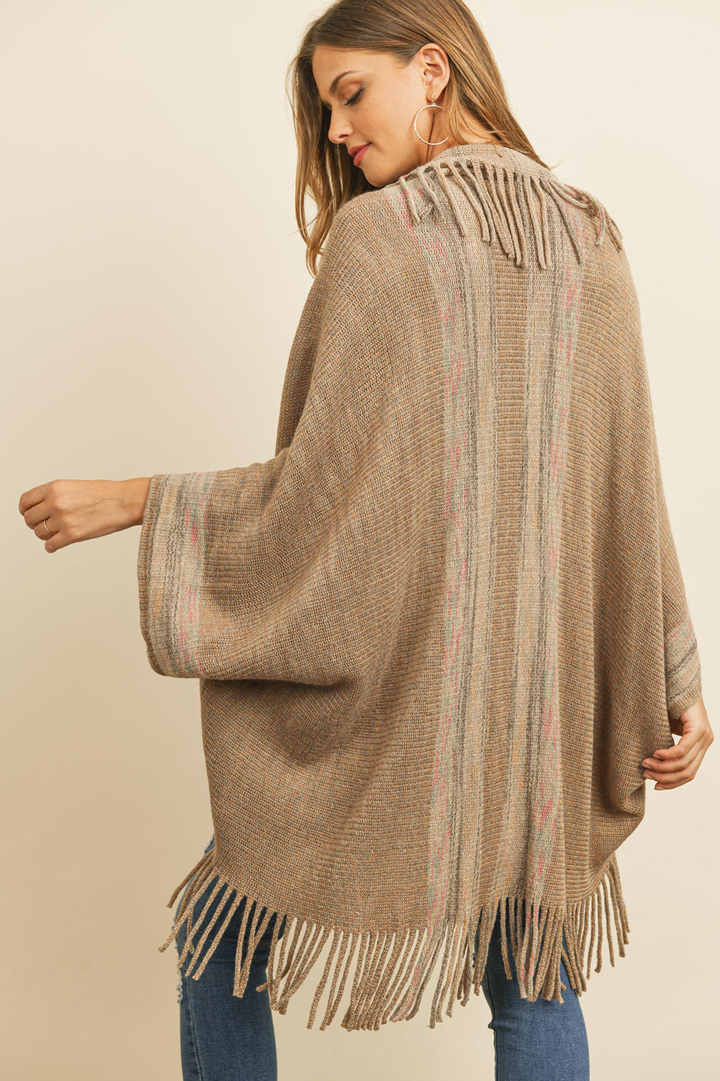 Someone is wearing a Fringe Stripe Open Front Kimono by Riah Fashion over a beige top and ripped jeans, standing against a plain background.