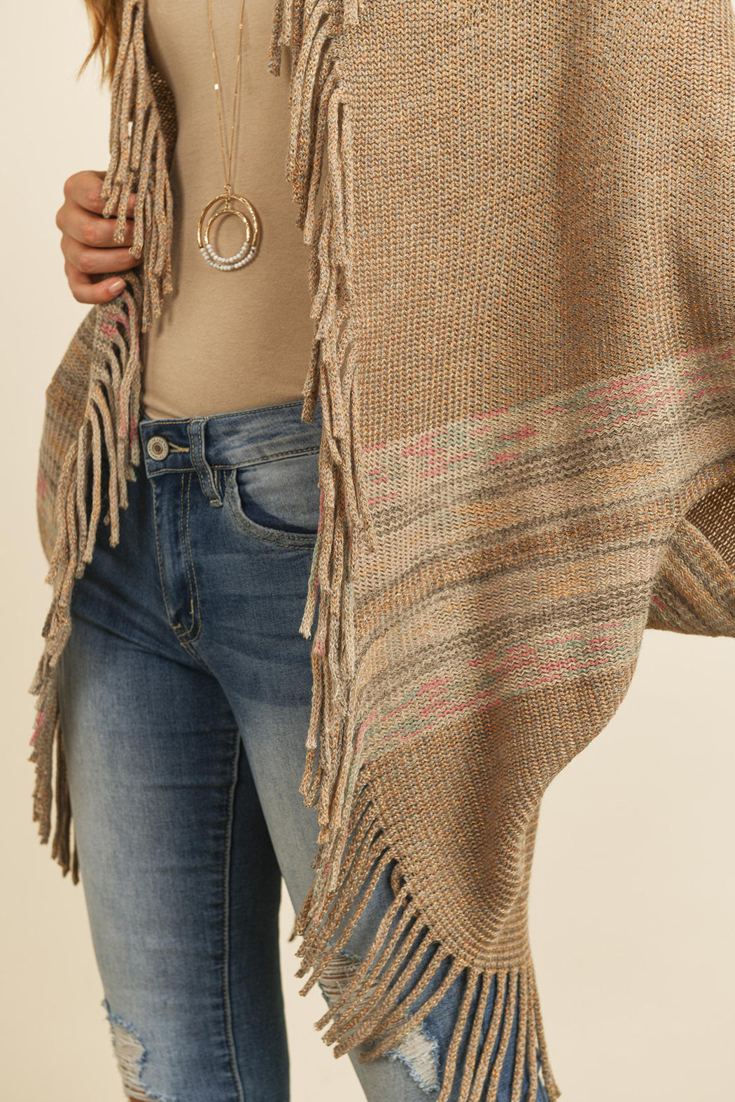 Someone is wearing a Fringe Stripe Open Front Kimono by Riah Fashion over a beige top and ripped jeans, standing against a plain background.