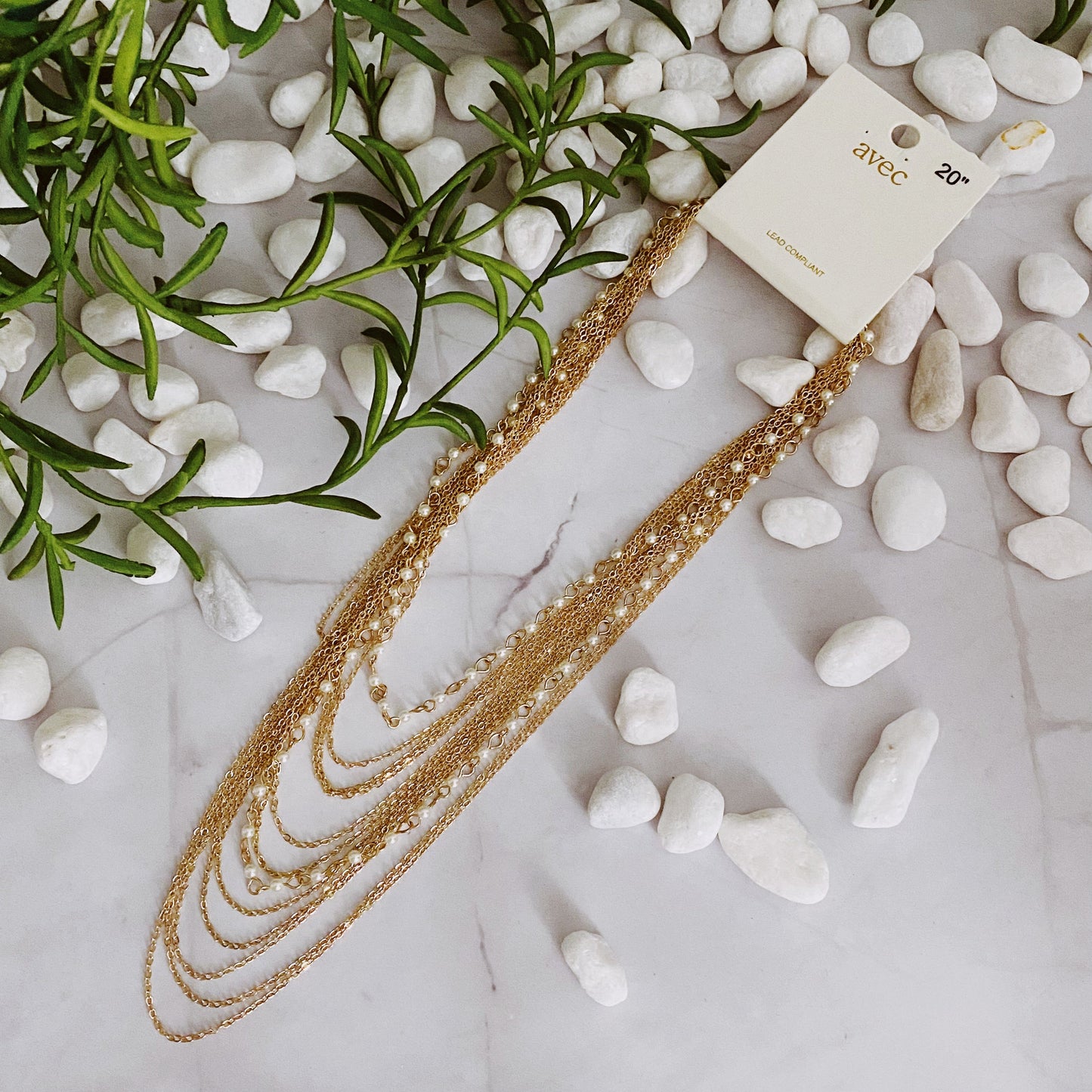 The Beautifully Draping Pearl and Chain Necklace by Ellison + Young is elegantly displayed on a white surface, showcasing its intricate chain designs.