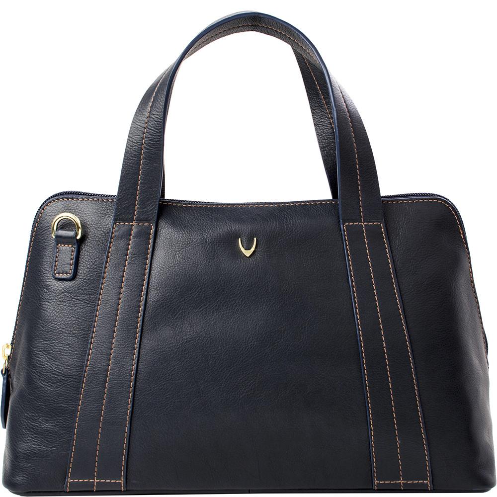 The Cerys Medium Leather Satchel by Hidesign is a red handbag with short handles and a detachable shoulder strap, featuring gold-tone hardware and a small gold emblem on the front.