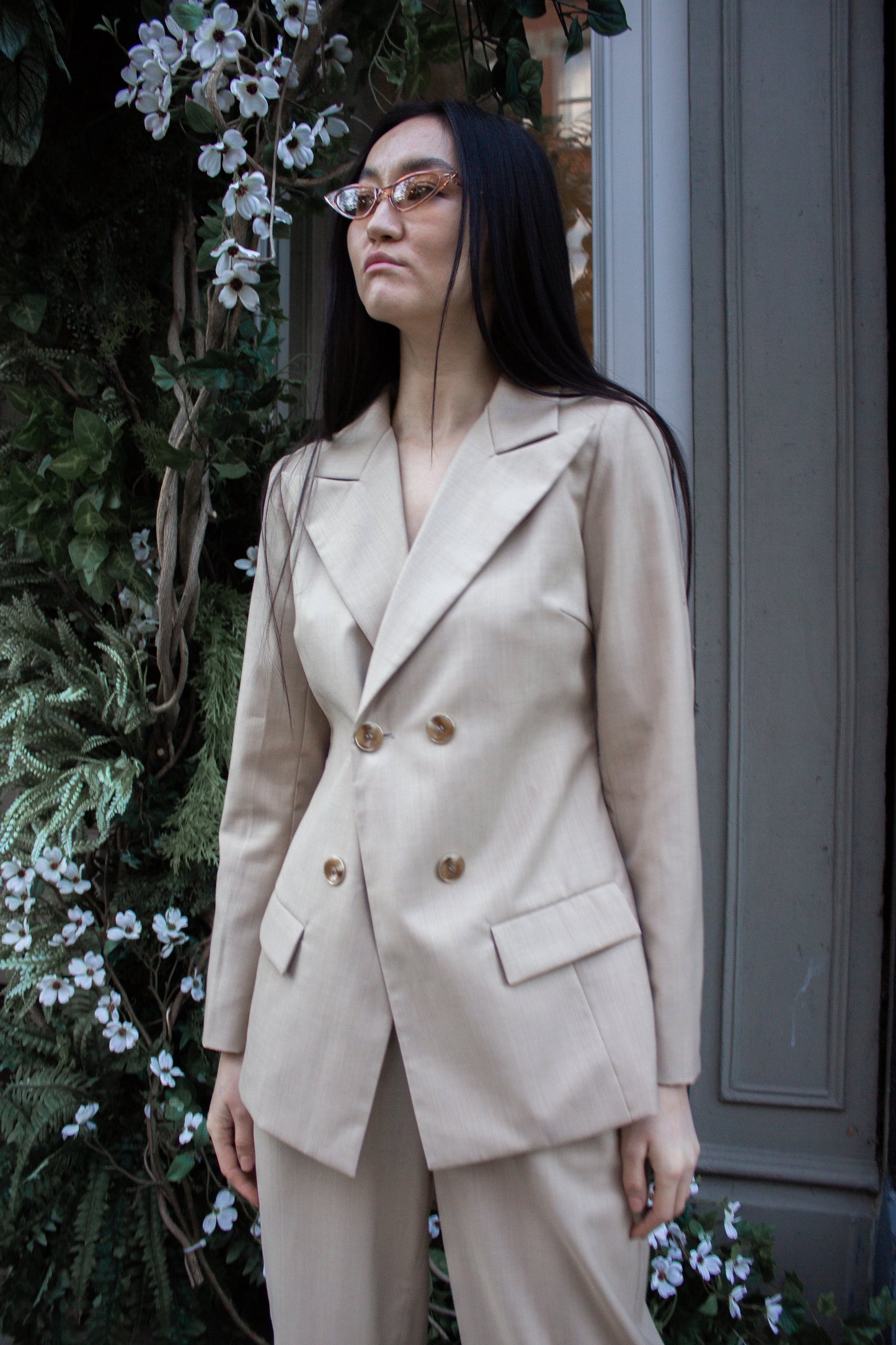 The Louise Blazer by Le Réussi® is a beige, double-breasted blazer featuring four buttons and two front pockets.