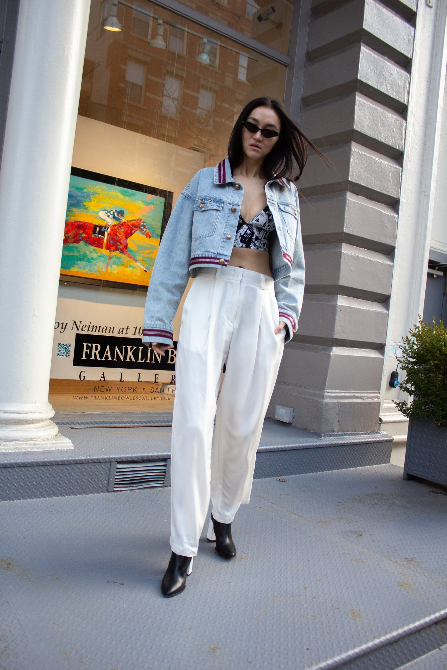 The Danielle Denim Jacket With Red Lining by Le Réussi® is a cropped light blue denim piece featuring red and white striped cuffs, waistband, and two chest pockets with button closures.