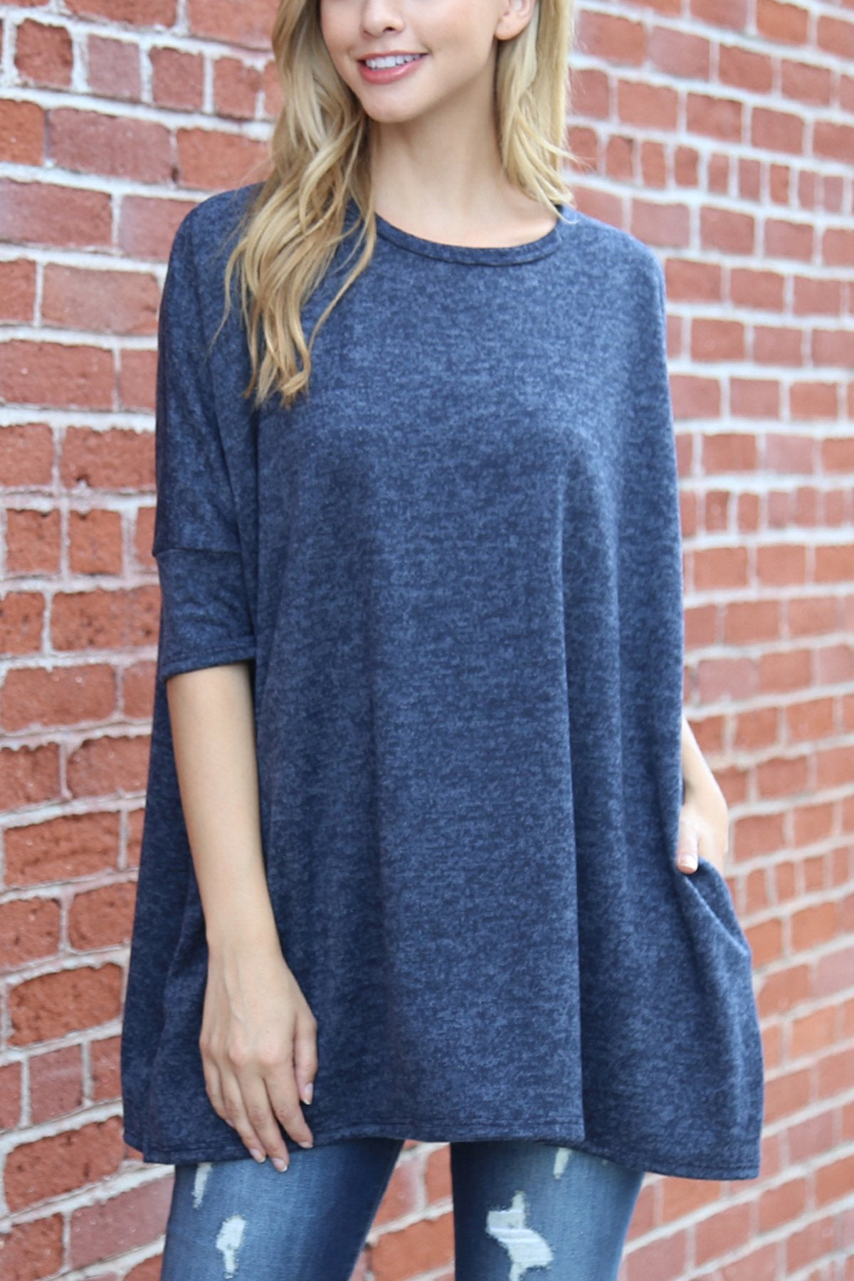 A woman stands against a beige background, wearing Riah Fashions Two Tone Hacci Oversized Dropped Shoulder Pocket Tunic in mustard, with hands in pockets and paired with ripped jeans.