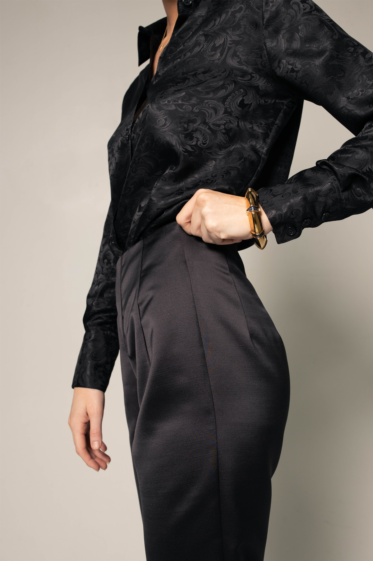 Someone wearing Le Réussi® Womens Trousers Pleated Pants and a black shirt stands against a plain background with one hand on their hip.