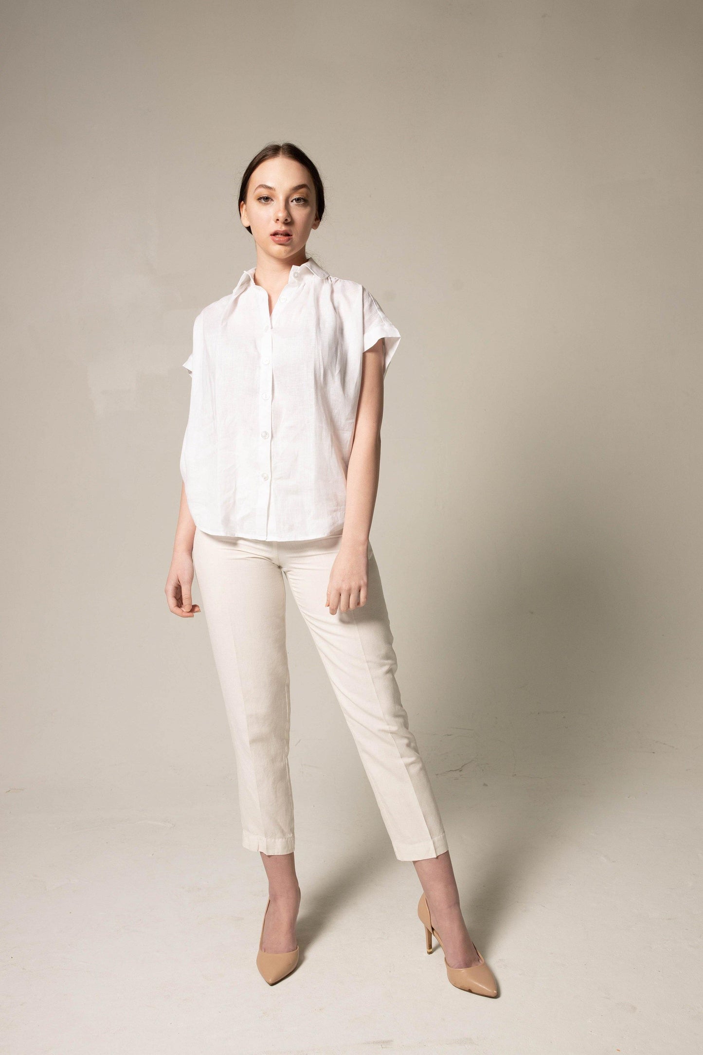 A person stands with crossed arms, wearing a Le Réussi® Womens Gather Collar Shirt in White and beige pants against a plain background.