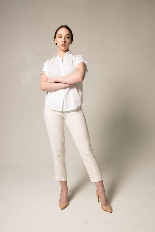 A person stands with crossed arms, wearing a Le Réussi® Womens Gather Collar Shirt in White and beige pants against a plain background.