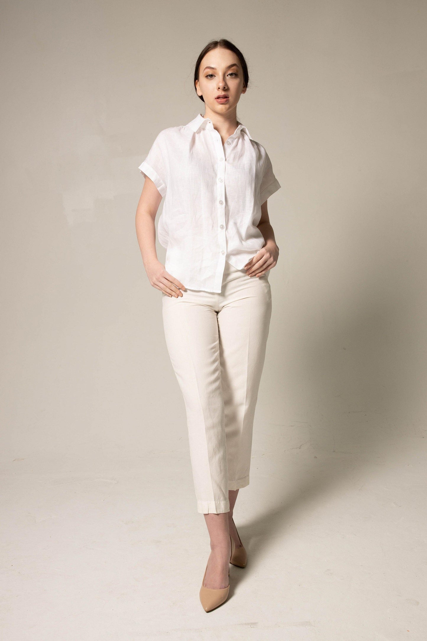 A person stands with crossed arms, wearing a Le Réussi® Womens Gather Collar Shirt in White and beige pants against a plain background.