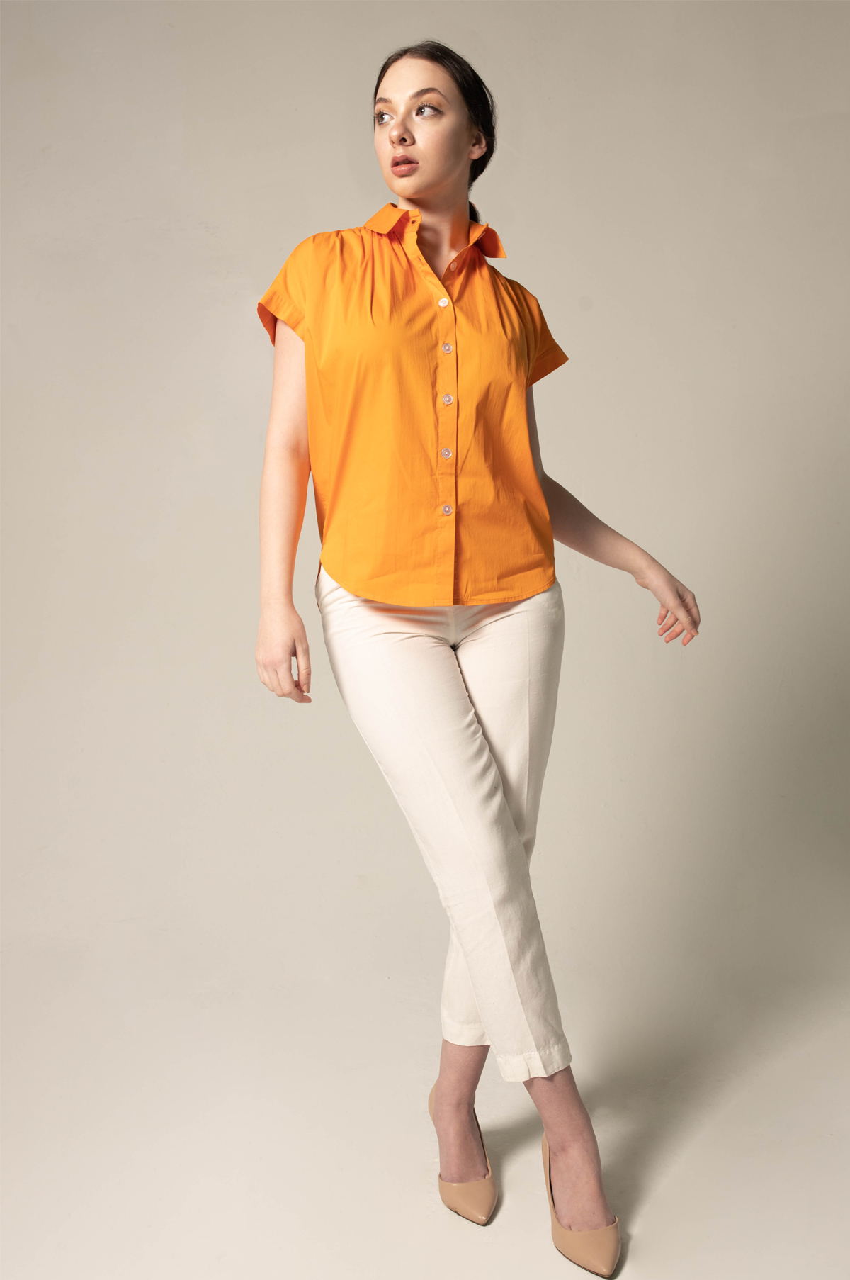 A person poses against a plain background, wearing the Womens Gather Collar Shirt in Orange by Le Réussi® and white pants.