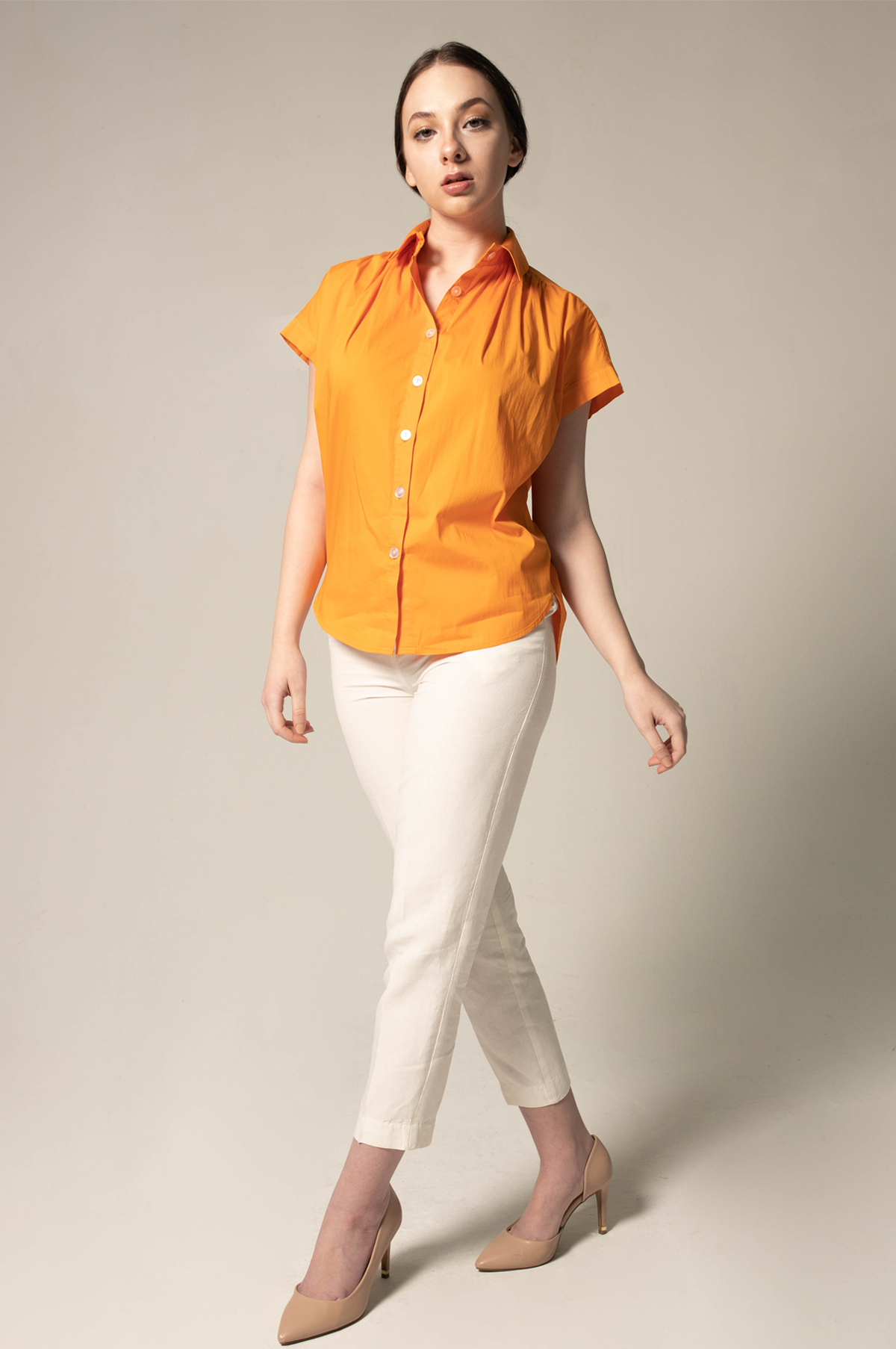 A person poses against a plain background, wearing the Womens Gather Collar Shirt in Orange by Le Réussi® and white pants.