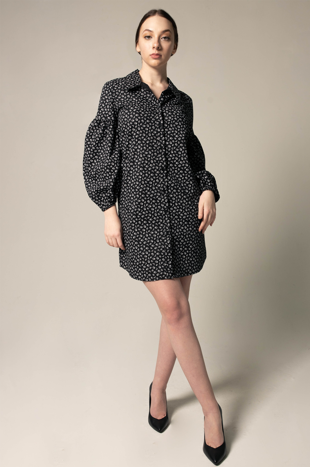 A person in a Le Réussi® Italian Cotton Shirt Dress with oversized sleeves in black floral and black heels stands against a neutral background.