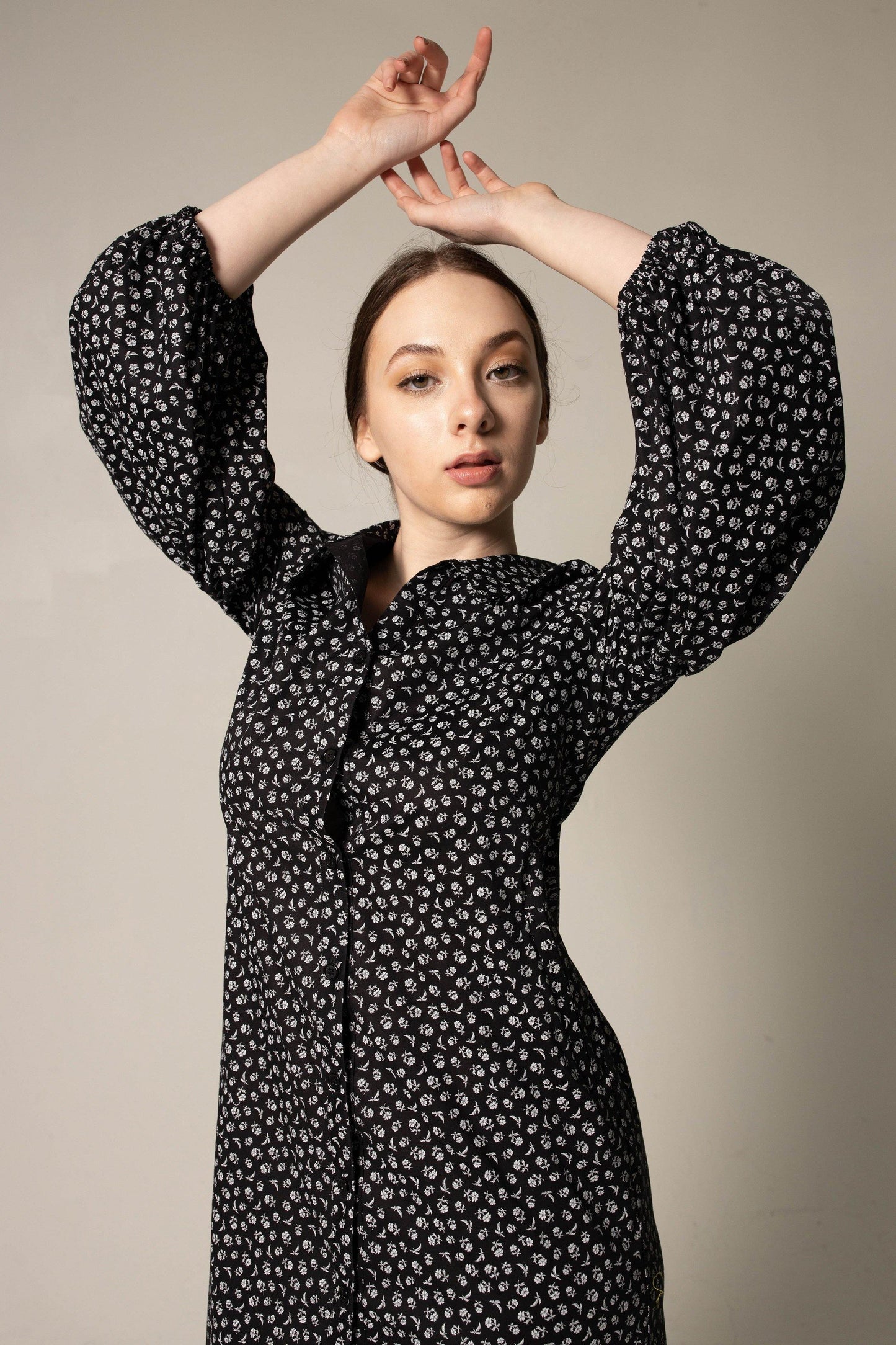 A person in a Le Réussi® Italian Cotton Shirt Dress with oversized sleeves in black floral and black heels stands against a neutral background.