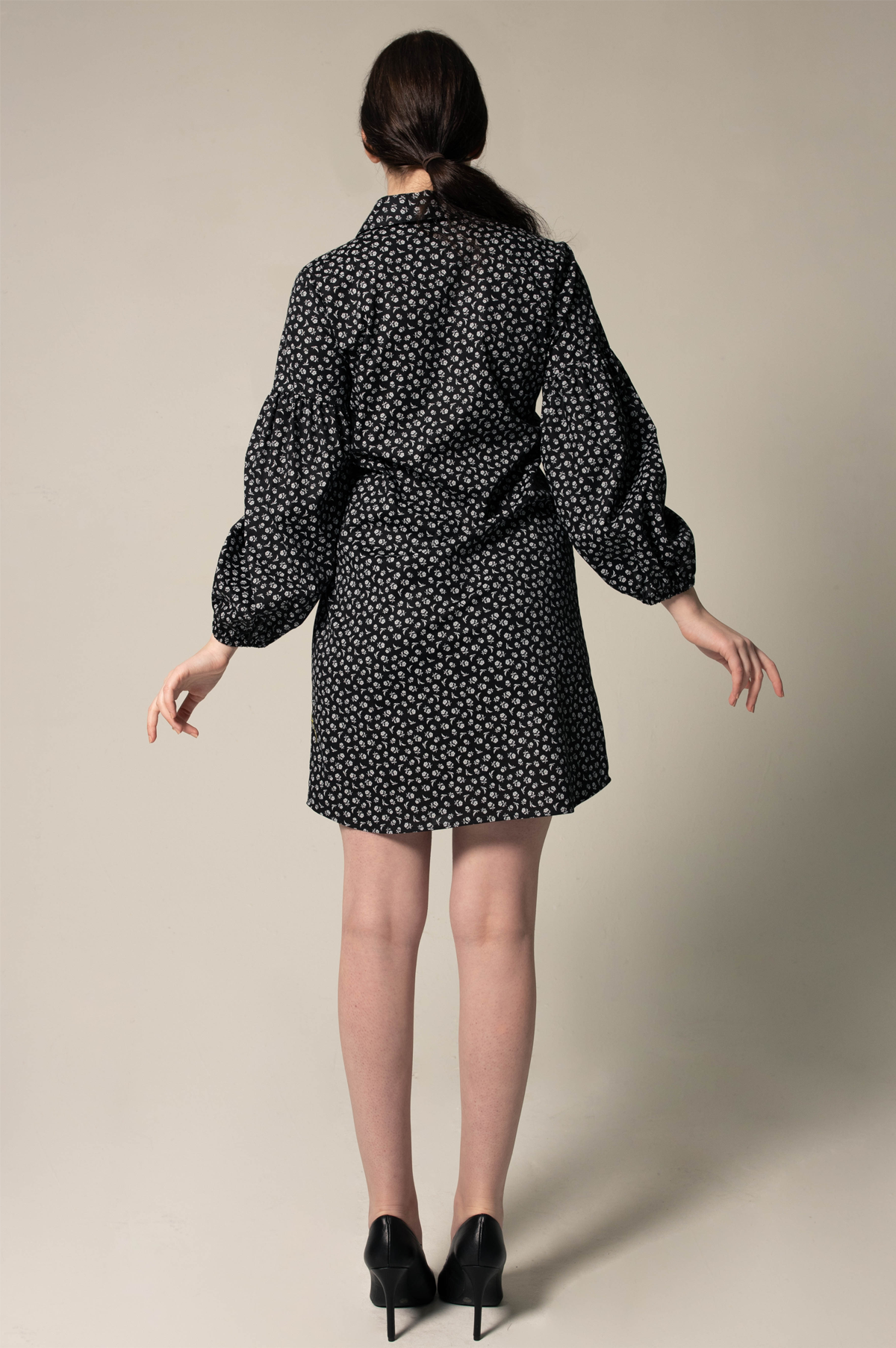 A person in a Le Réussi® Italian Cotton Shirt Dress with oversized sleeves in black floral and black heels stands against a neutral background.