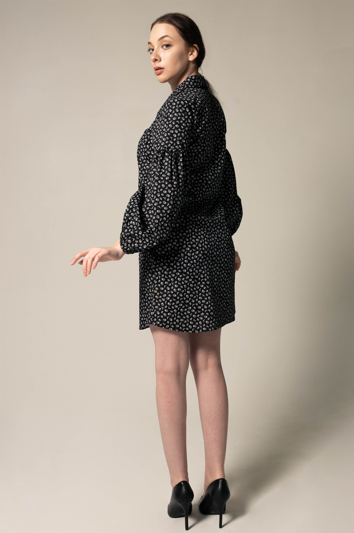 A person in a Le Réussi® Italian Cotton Shirt Dress with oversized sleeves in black floral and black heels stands against a neutral background.