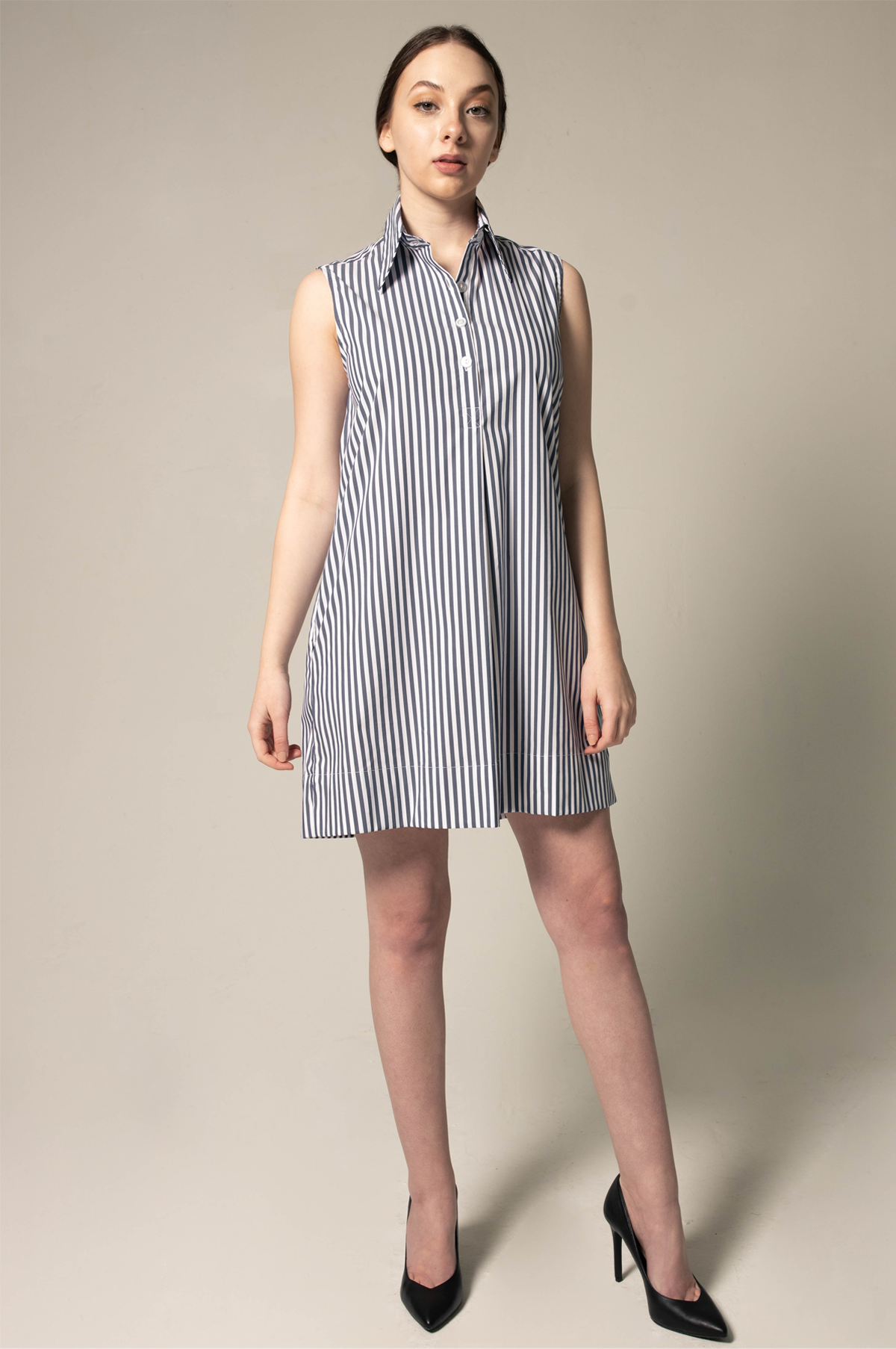 A model showcases the Italian Cotton Blue Stripe Sleeveless Dress by Le Réussi®, paired with black heels against a plain beige background.