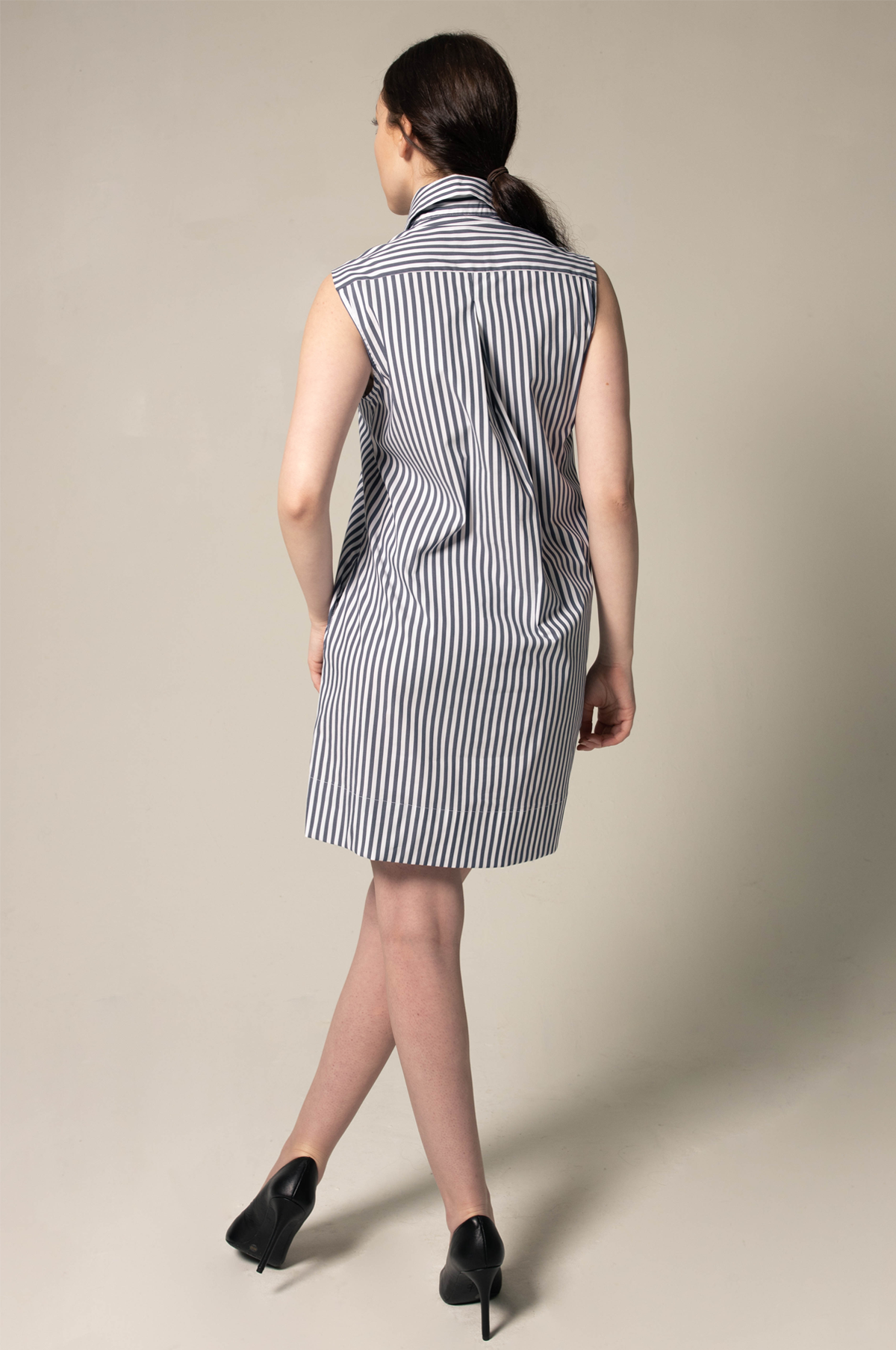A model showcases the Italian Cotton Blue Stripe Sleeveless Dress by Le Réussi®, paired with black heels against a plain beige background.
