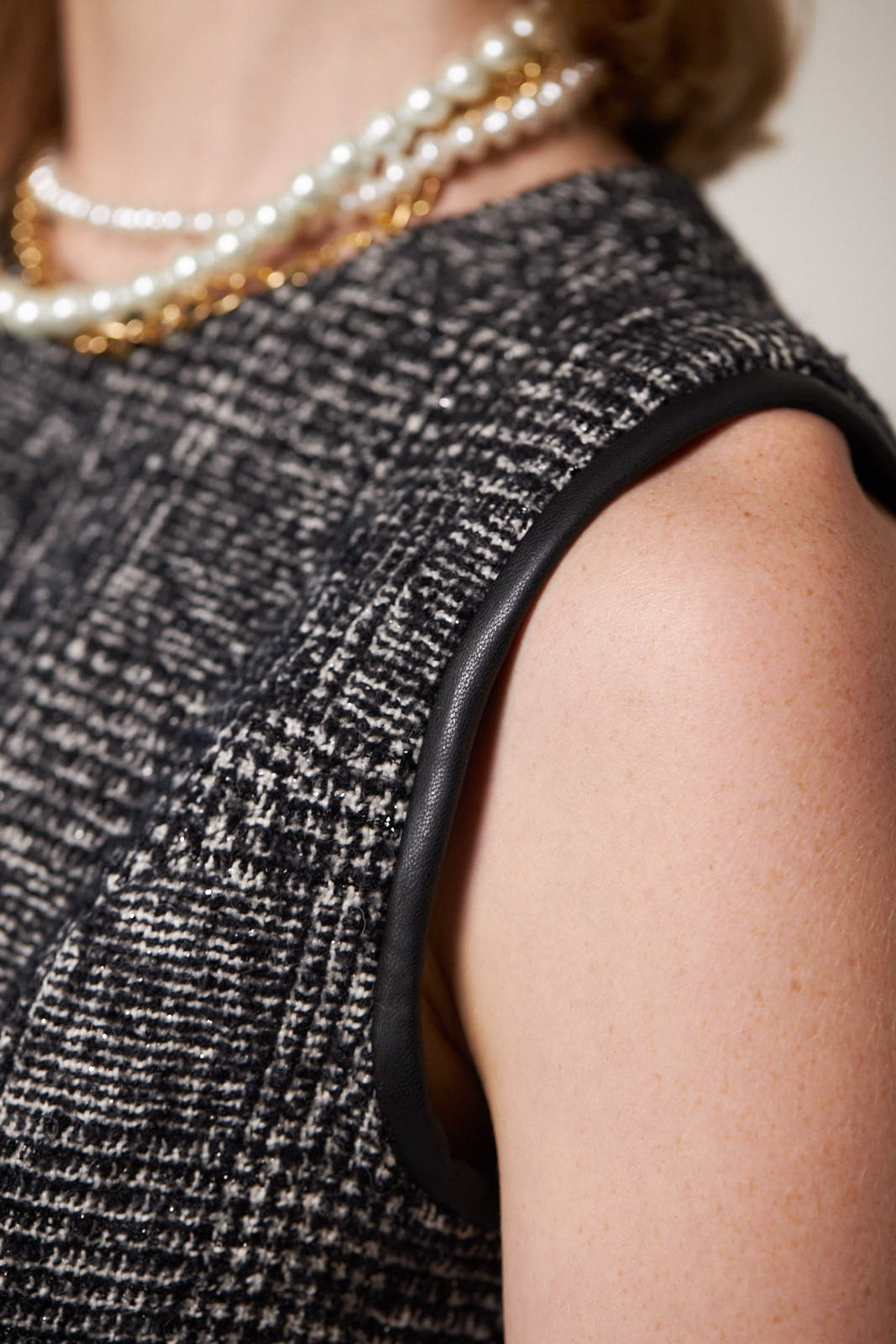 A person standing against a white background wears the Boss Woman Tweed Dress by Le Réussi®, accessorized with layered necklaces, a black belt, and black ankle boots.
