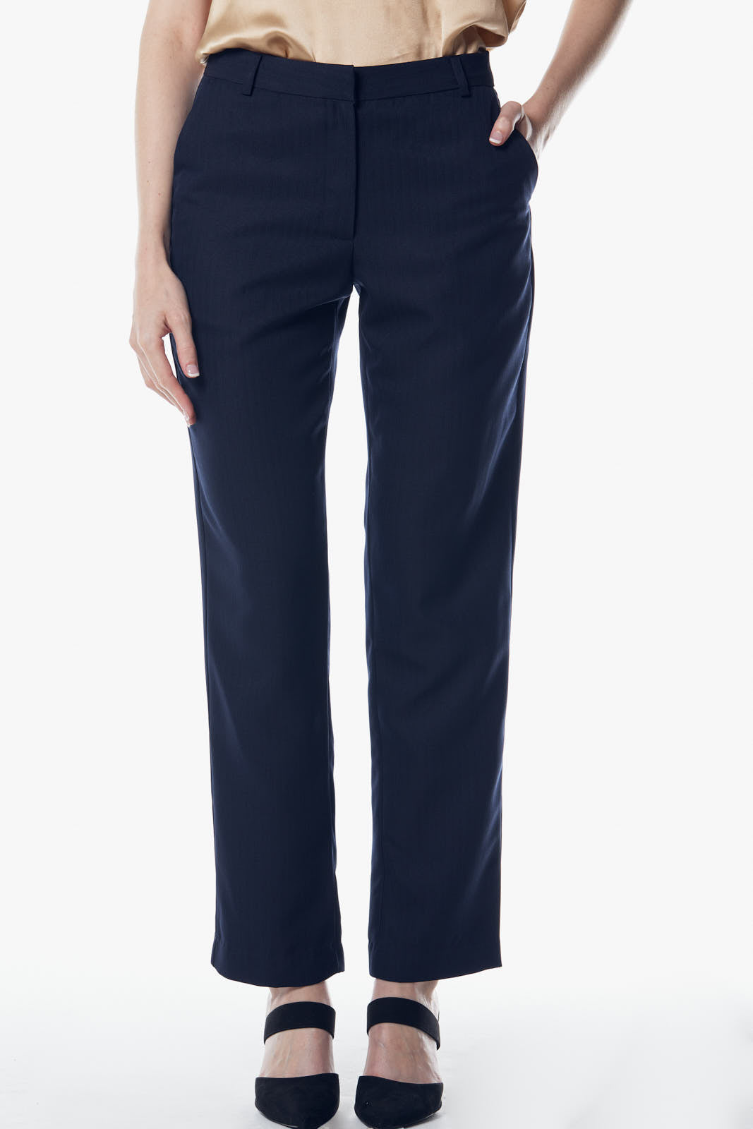Person in Italian Wool Skinny Pants by Le Réussi®, a dark suit, heels, and a scarf stands against a plain background.