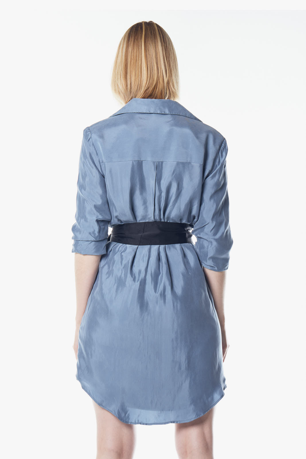 A person stands against a plain background, wearing the Cielo Blue Blazer Dress by Le Réussi®, accented with a black belt and paired with black ankle boots.