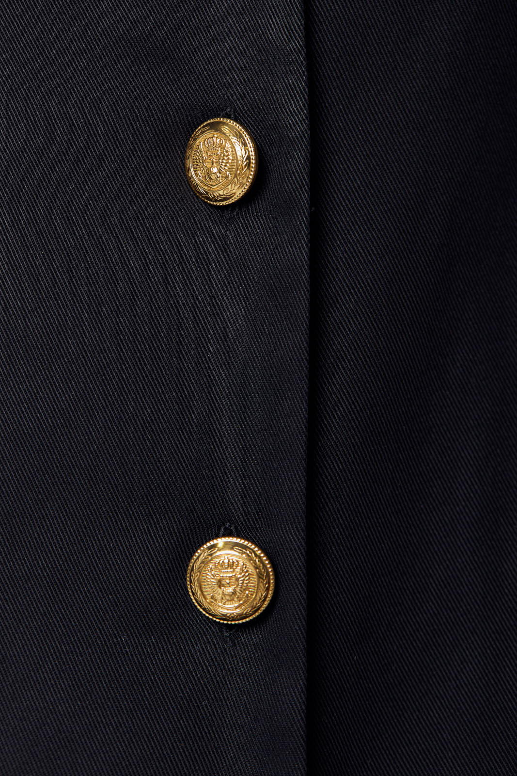 A woman in a black Linen Long Jacket by Le Réussi® stands against a white background, paired with black strappy heels.