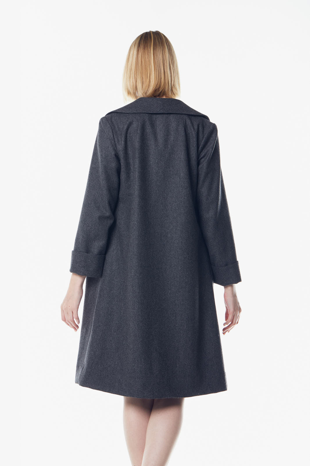 A person poses in a dark dress and the Power Woman Worsted Flannel Long Jacket in Dark Grey by Le Réussi®, against a white background, wearing black high heels.