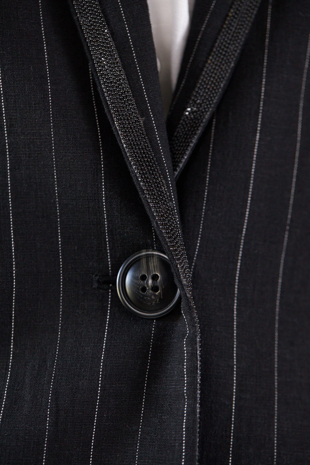 A person wearing the Le Réussi® Power Woman- Black/White Stripes Jacket with a white shirt stands stylishly with one hand in their pocket.