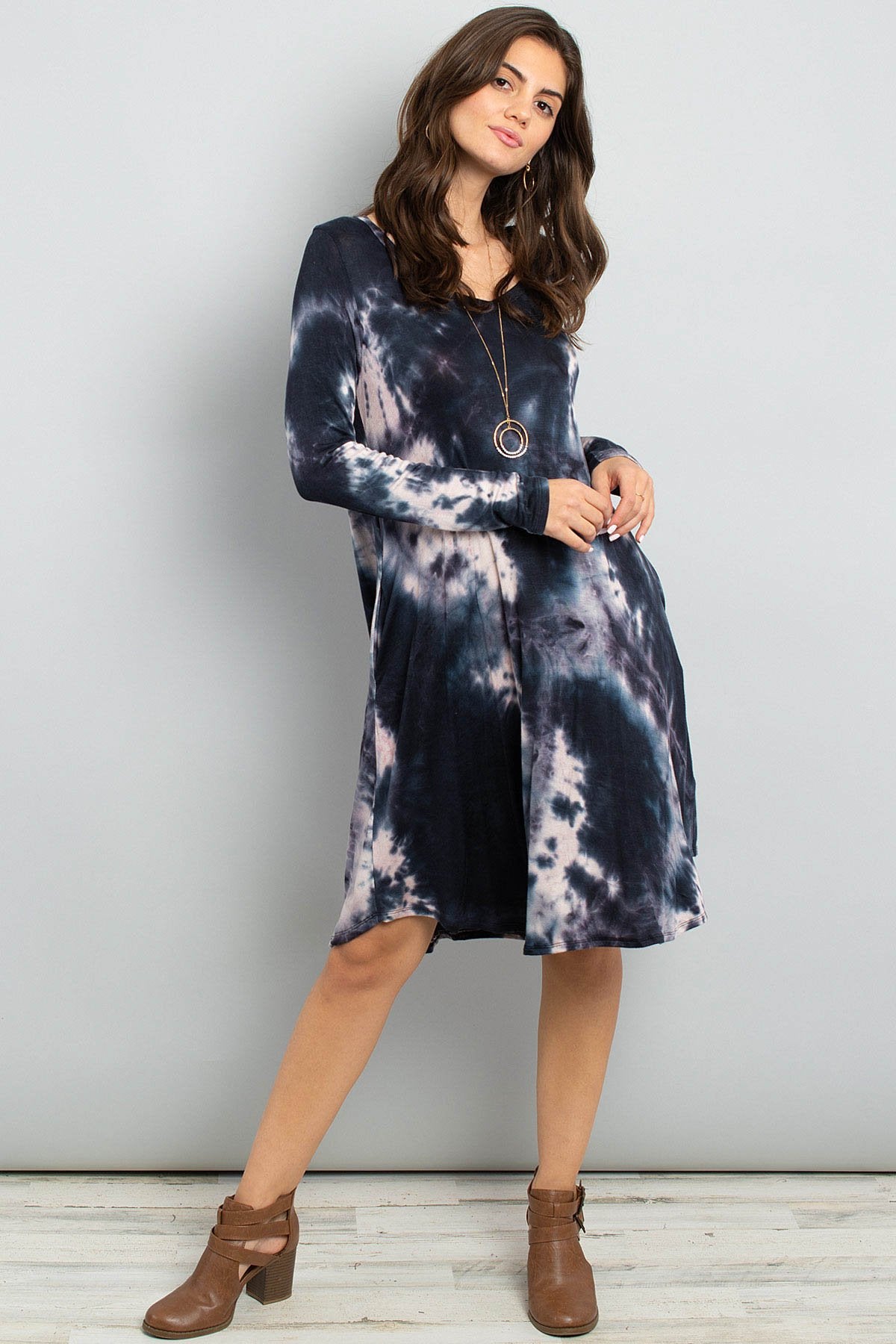 A woman in a purple Tie Dye V-Neck Rounded Hem Midi Dress by Riah Fashion, touching her hair, stands against a beige background.