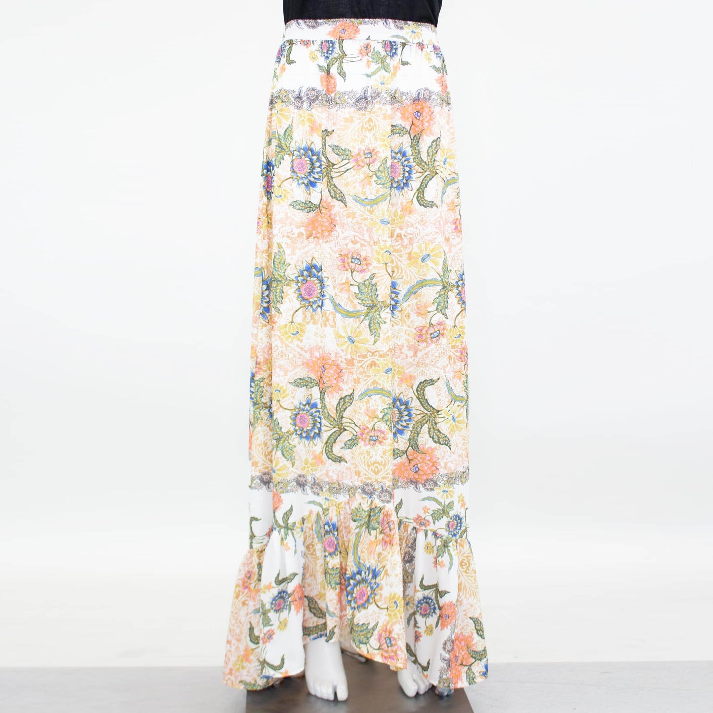 Stylespects Flared Bottom Floral Maxi Skirt showcases a ruffled hem with an array of orange, pink, blue, and green patterns set against a white background.