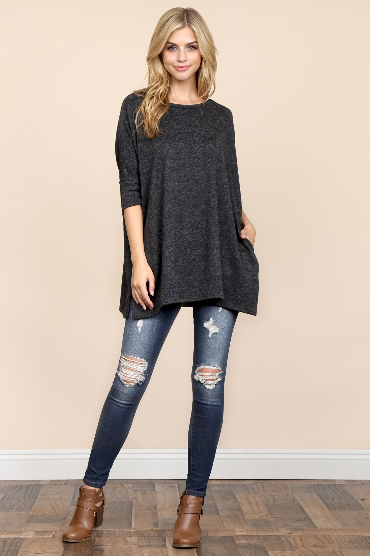 A woman stands against a beige background, wearing Riah Fashions Two Tone Hacci Oversized Dropped Shoulder Pocket Tunic in mustard, with hands in pockets and paired with ripped jeans.