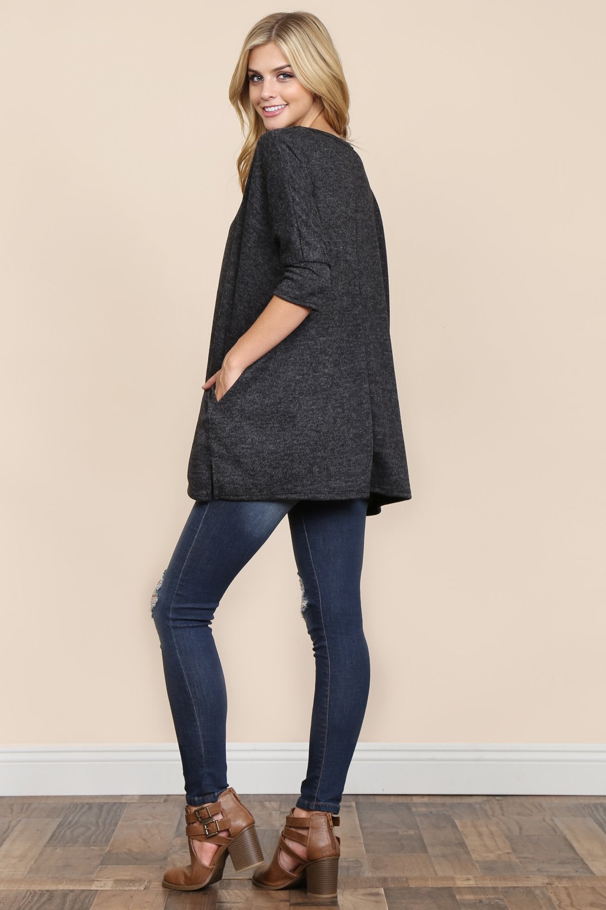 A woman stands against a beige background, wearing Riah Fashions Two Tone Hacci Oversized Dropped Shoulder Pocket Tunic in mustard, with hands in pockets and paired with ripped jeans.