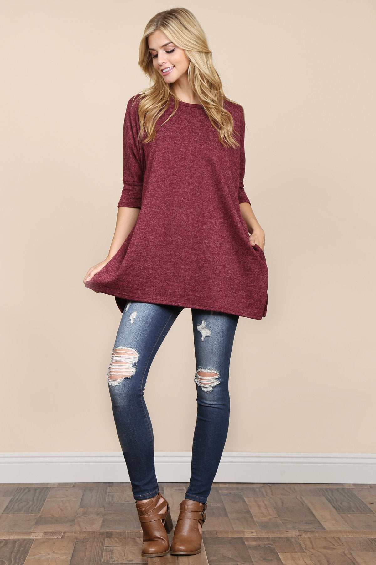 A woman stands against a beige background, wearing Riah Fashions Two Tone Hacci Oversized Dropped Shoulder Pocket Tunic in mustard, with hands in pockets and paired with ripped jeans.