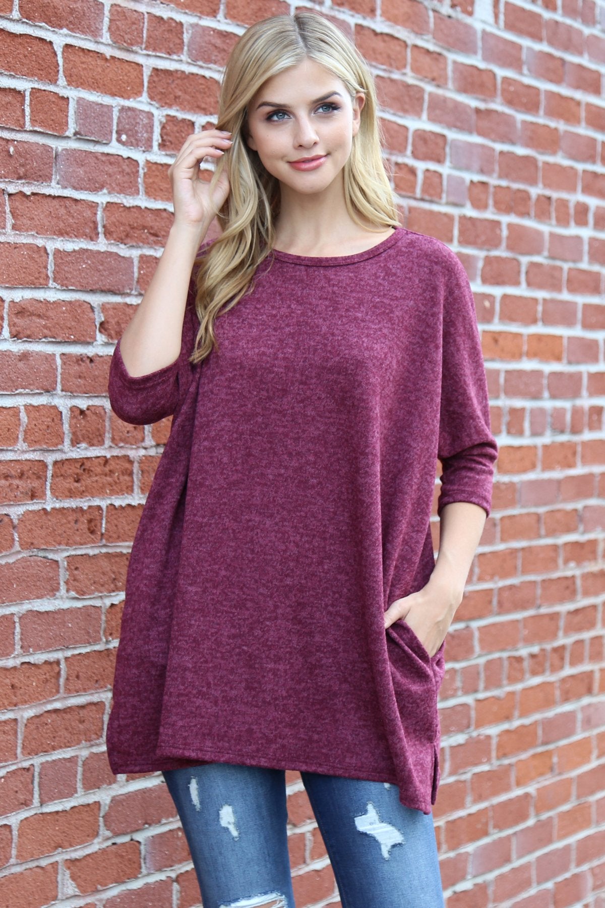 A woman stands against a beige background, wearing Riah Fashions Two Tone Hacci Oversized Dropped Shoulder Pocket Tunic in mustard, with hands in pockets and paired with ripped jeans.