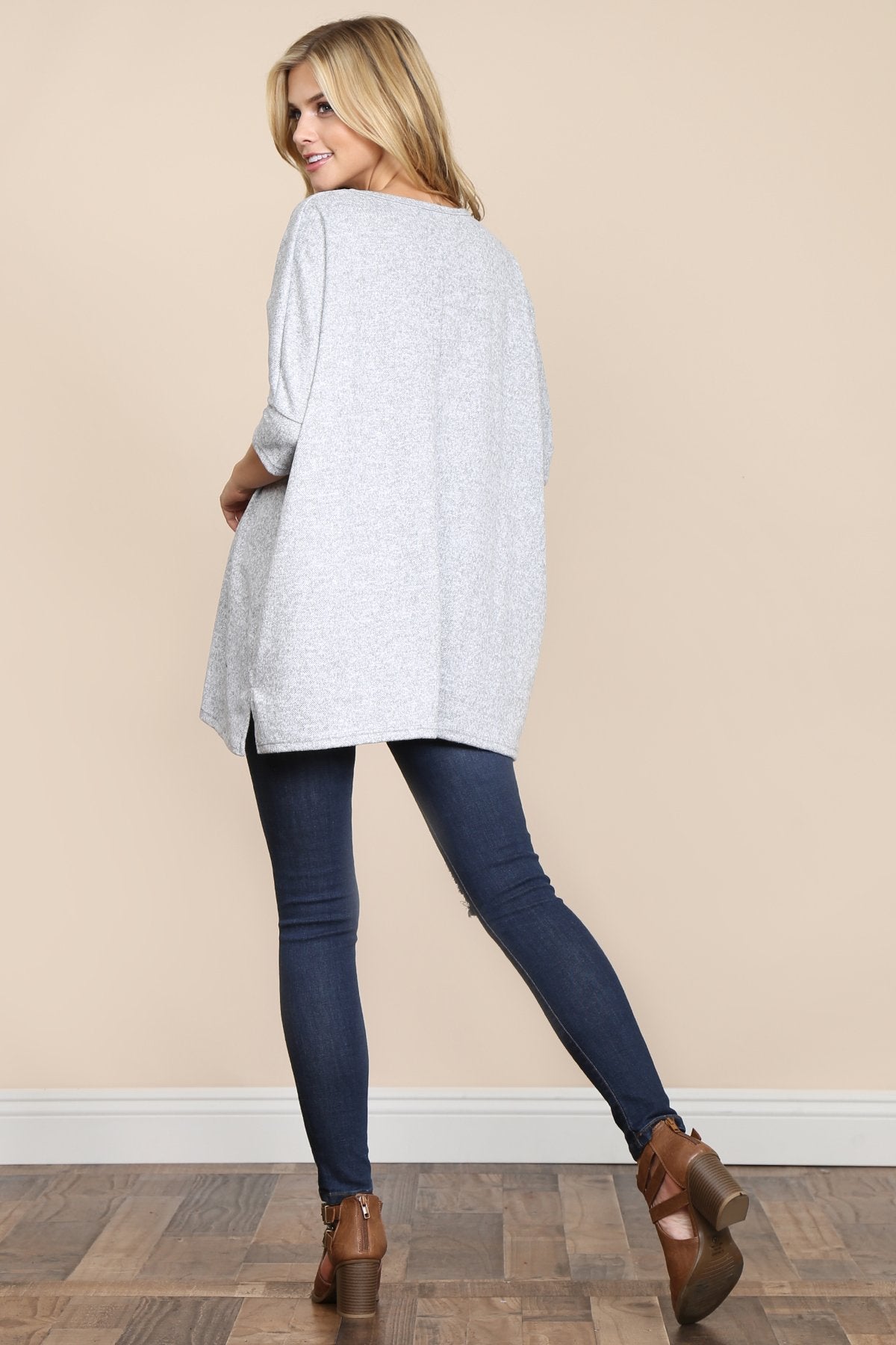 A woman stands against a beige background, wearing Riah Fashions Two Tone Hacci Oversized Dropped Shoulder Pocket Tunic in mustard, with hands in pockets and paired with ripped jeans.