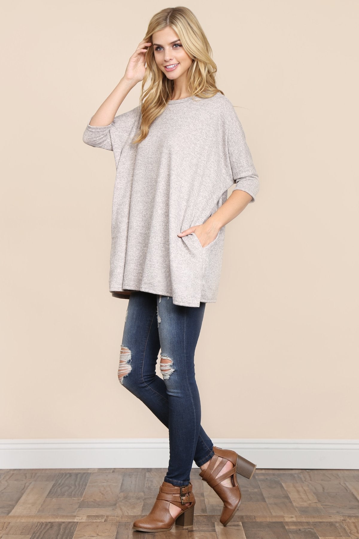 A woman stands against a beige background, wearing Riah Fashions Two Tone Hacci Oversized Dropped Shoulder Pocket Tunic in mustard, with hands in pockets and paired with ripped jeans.