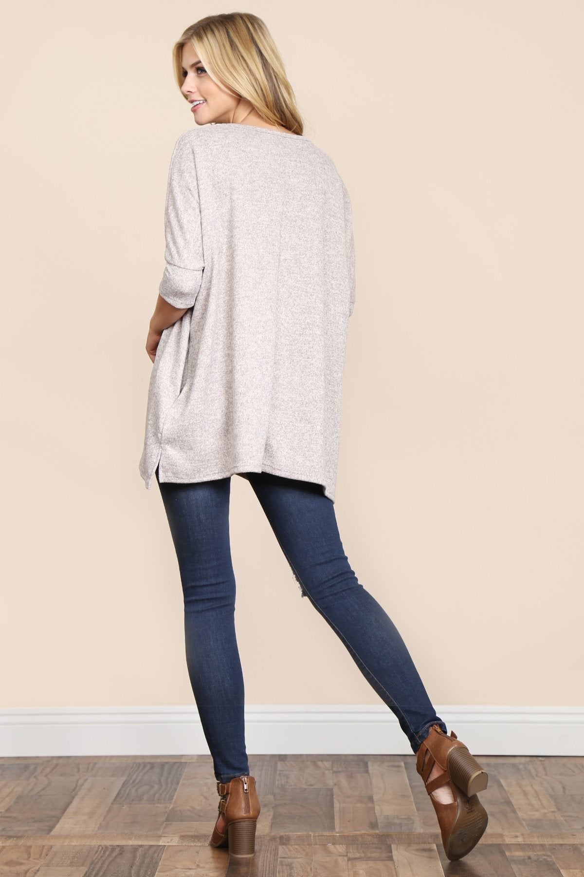 A woman stands against a beige background, wearing Riah Fashions Two Tone Hacci Oversized Dropped Shoulder Pocket Tunic in mustard, with hands in pockets and paired with ripped jeans.